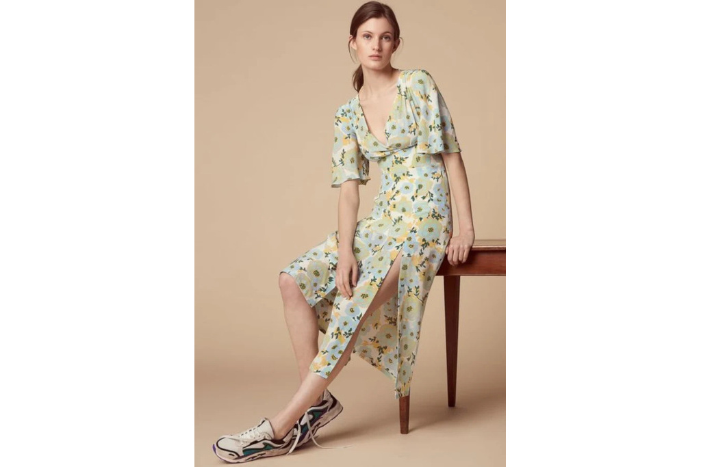Woman in dress and trainers leaning against table