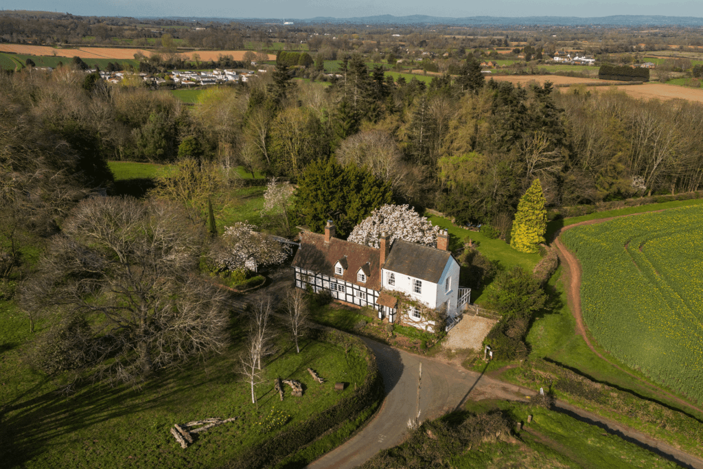 Aerial view of a Tudor farmhouse with a magnolia tree in the garden.