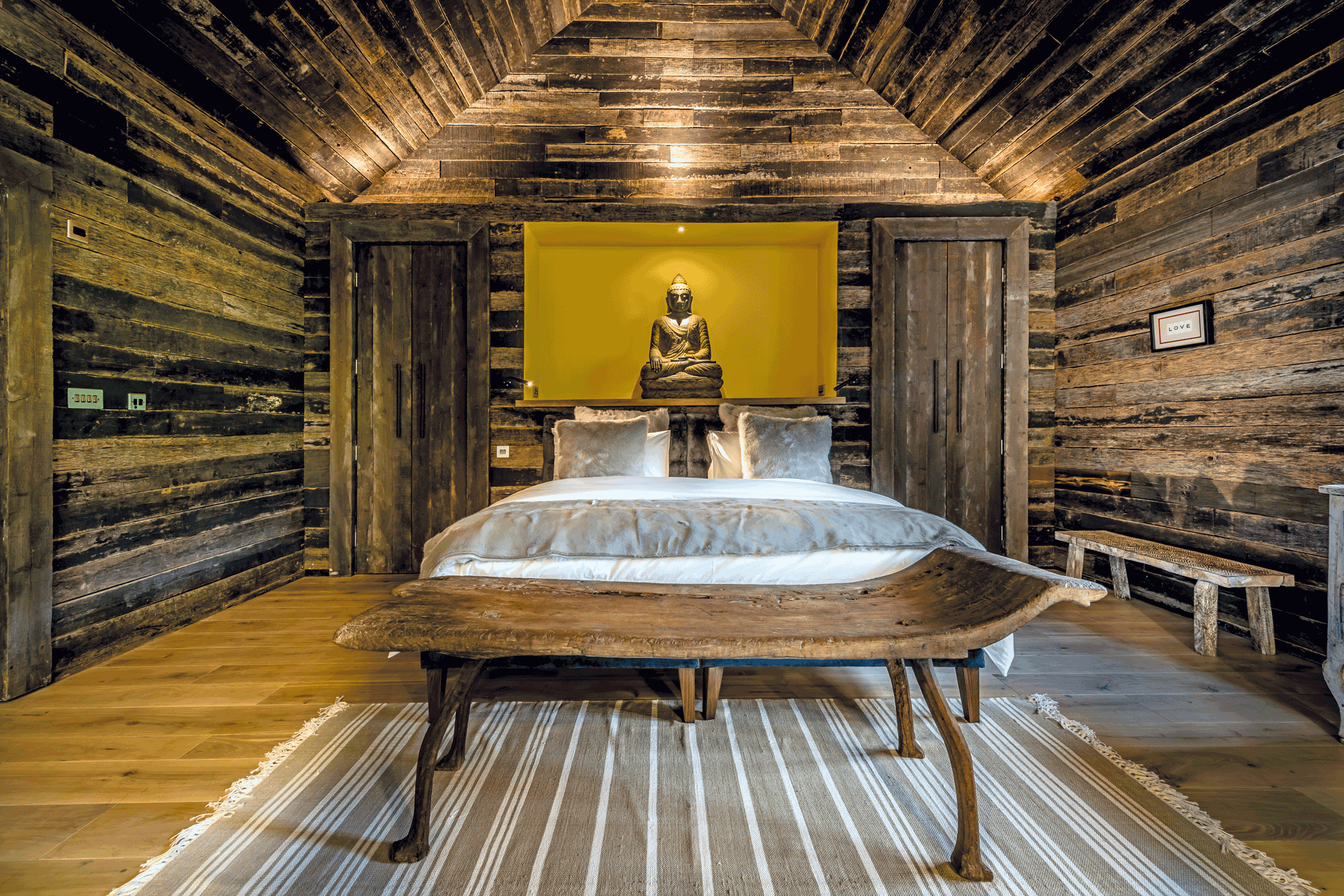 Bedroom at Yeotown wellness retreat featuring wooden panelled walls and a yellow feature wall behind the bed.