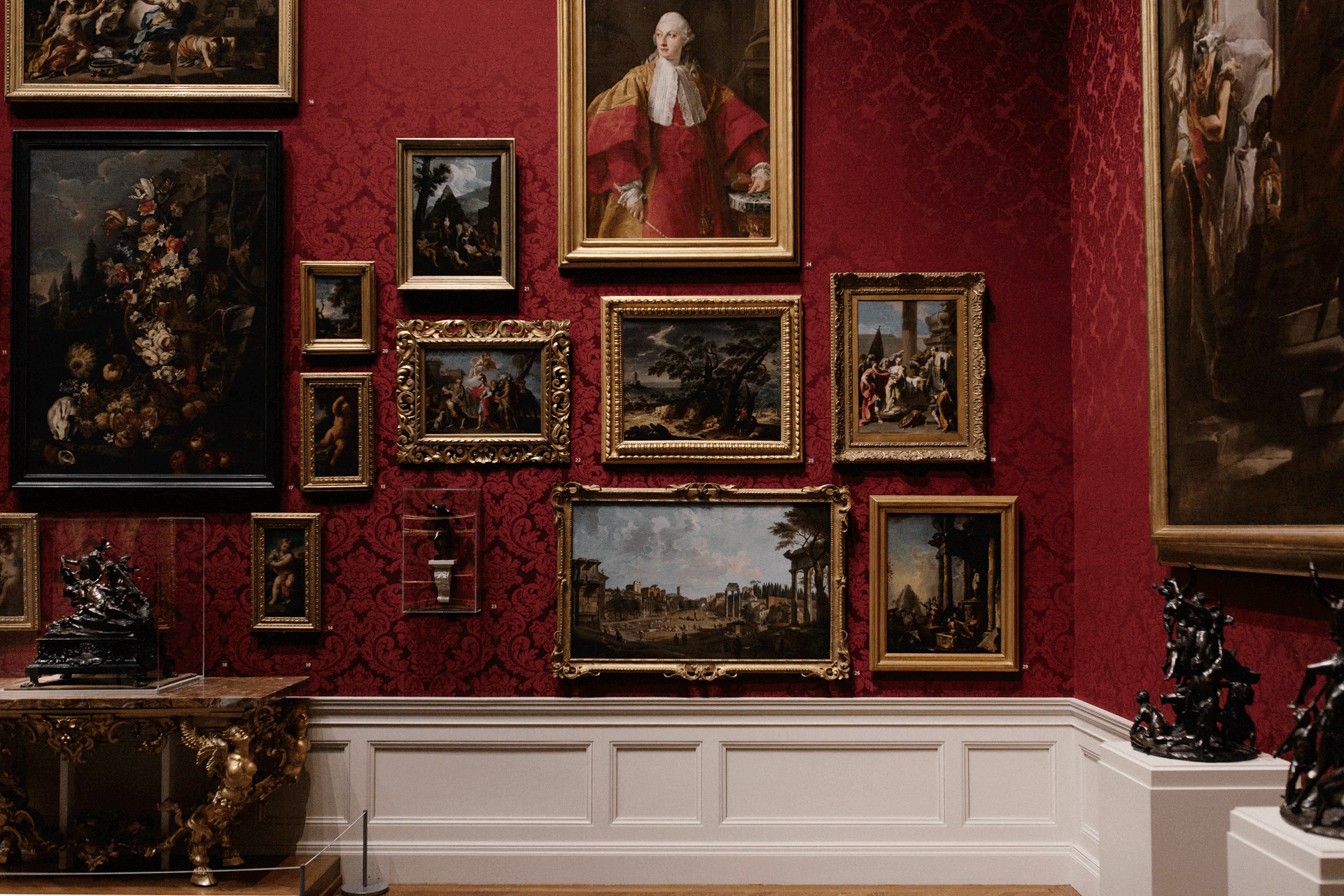 Museum with red wall and gilded picture frames.