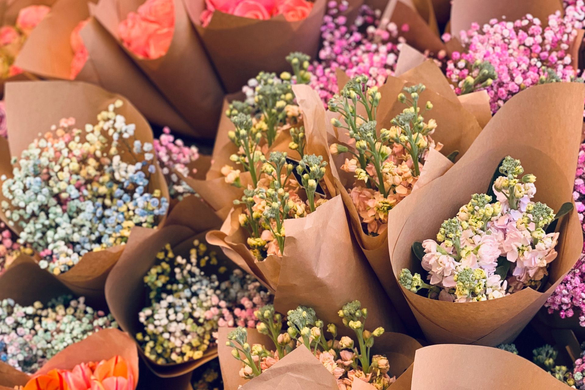 bouquets of flowers wrapped in brown paper at a market