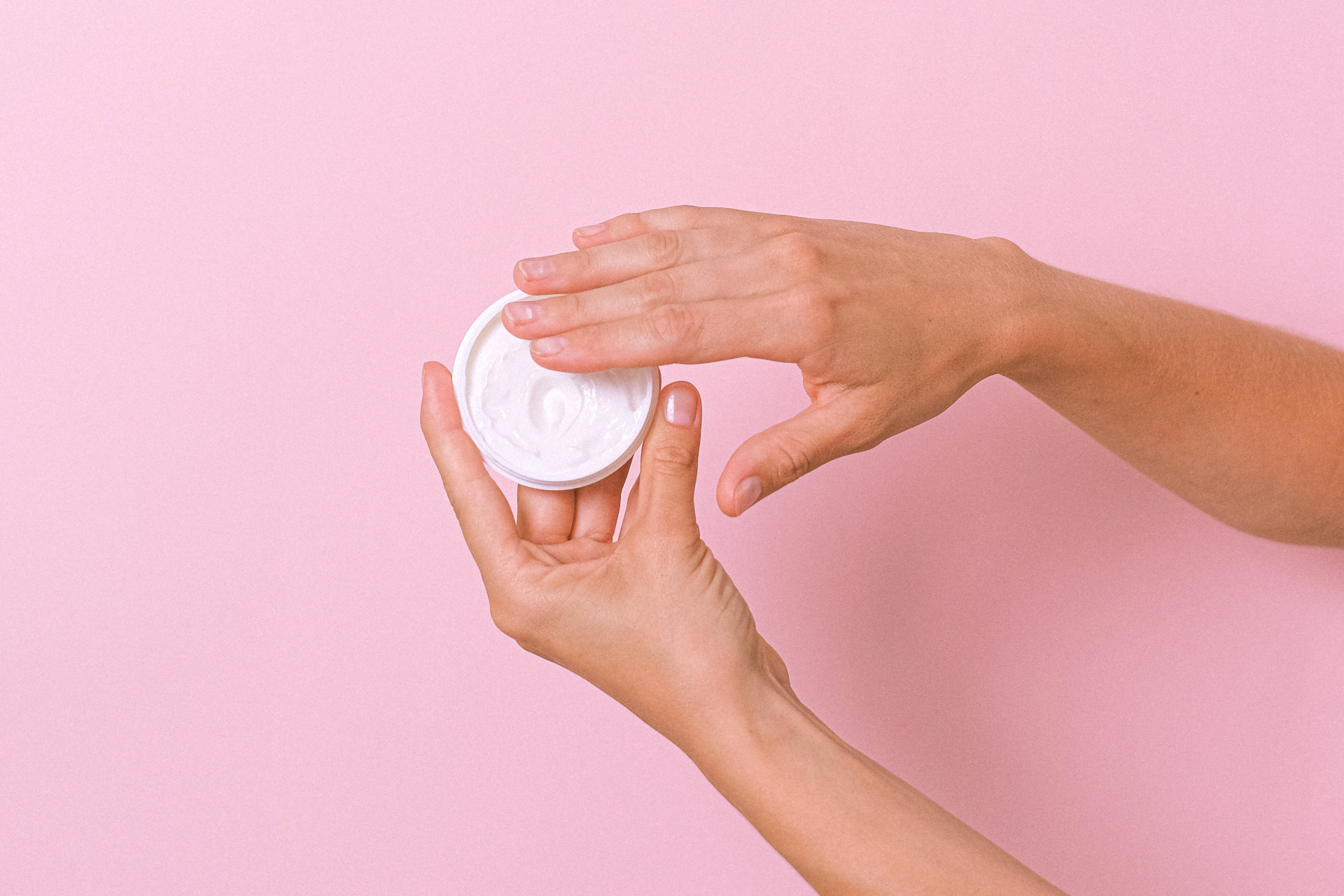 Hands holding white tub on pink background