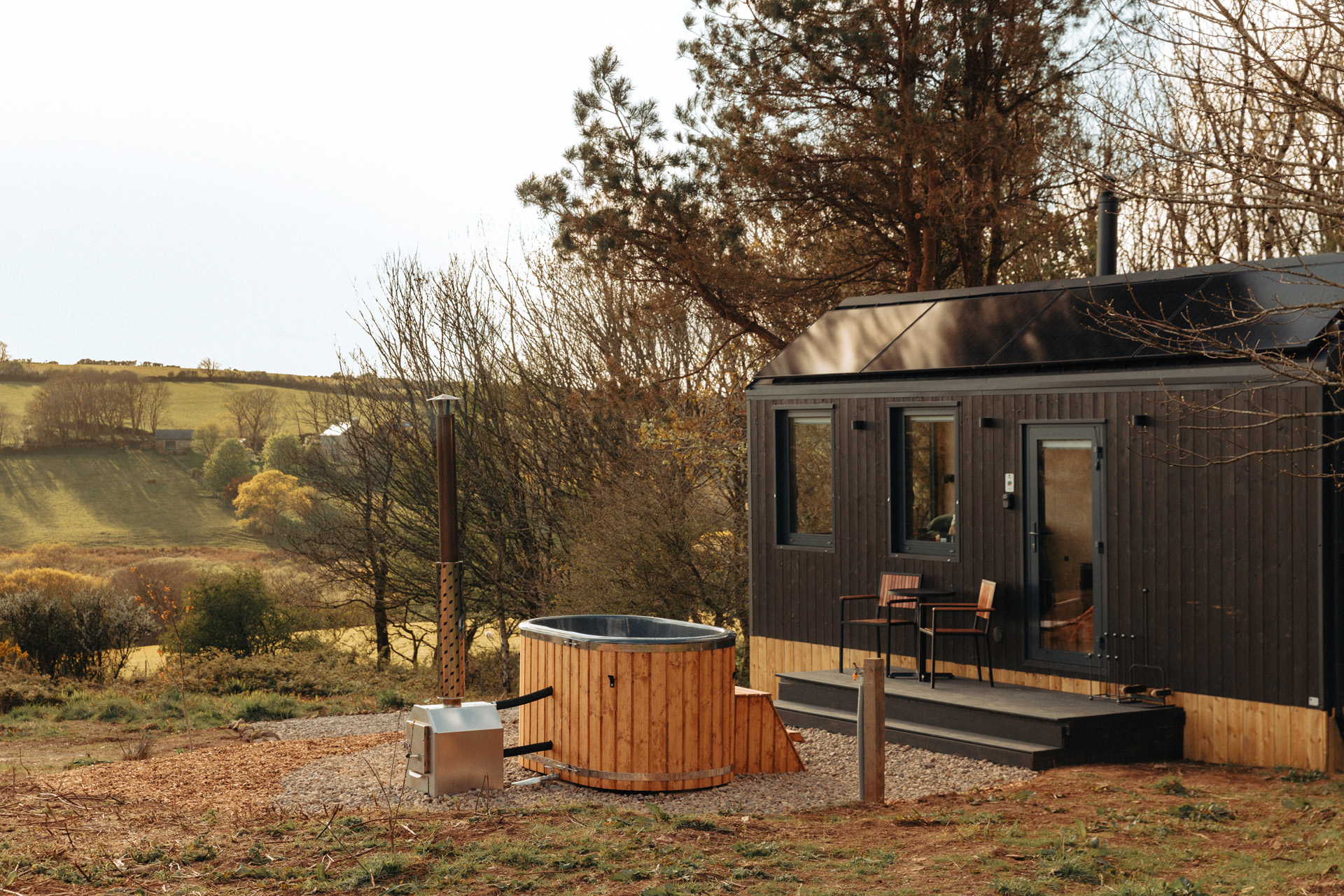 A cabin with a hot tub overlooking farmland