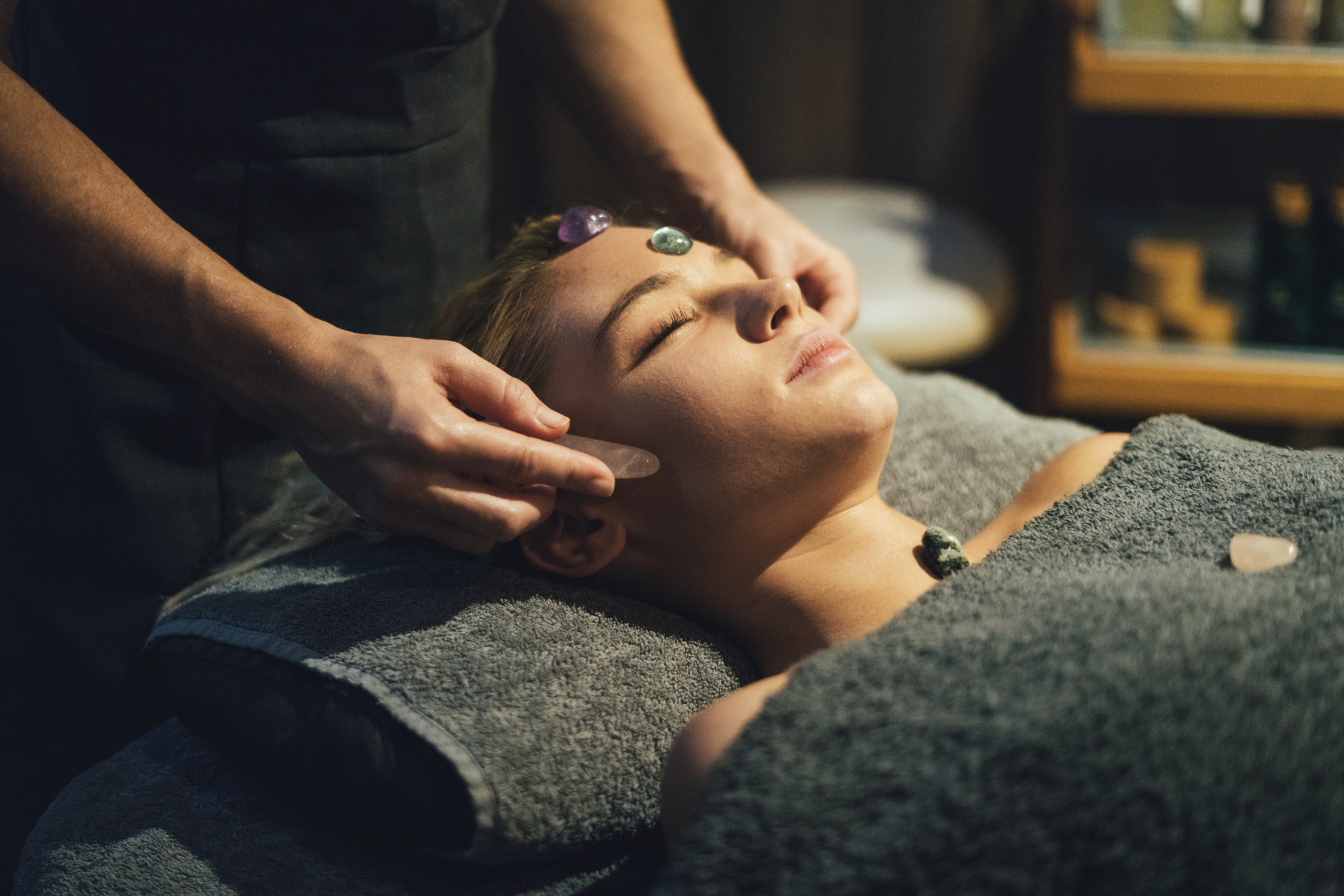 Woman receiving crystal massage around head and face