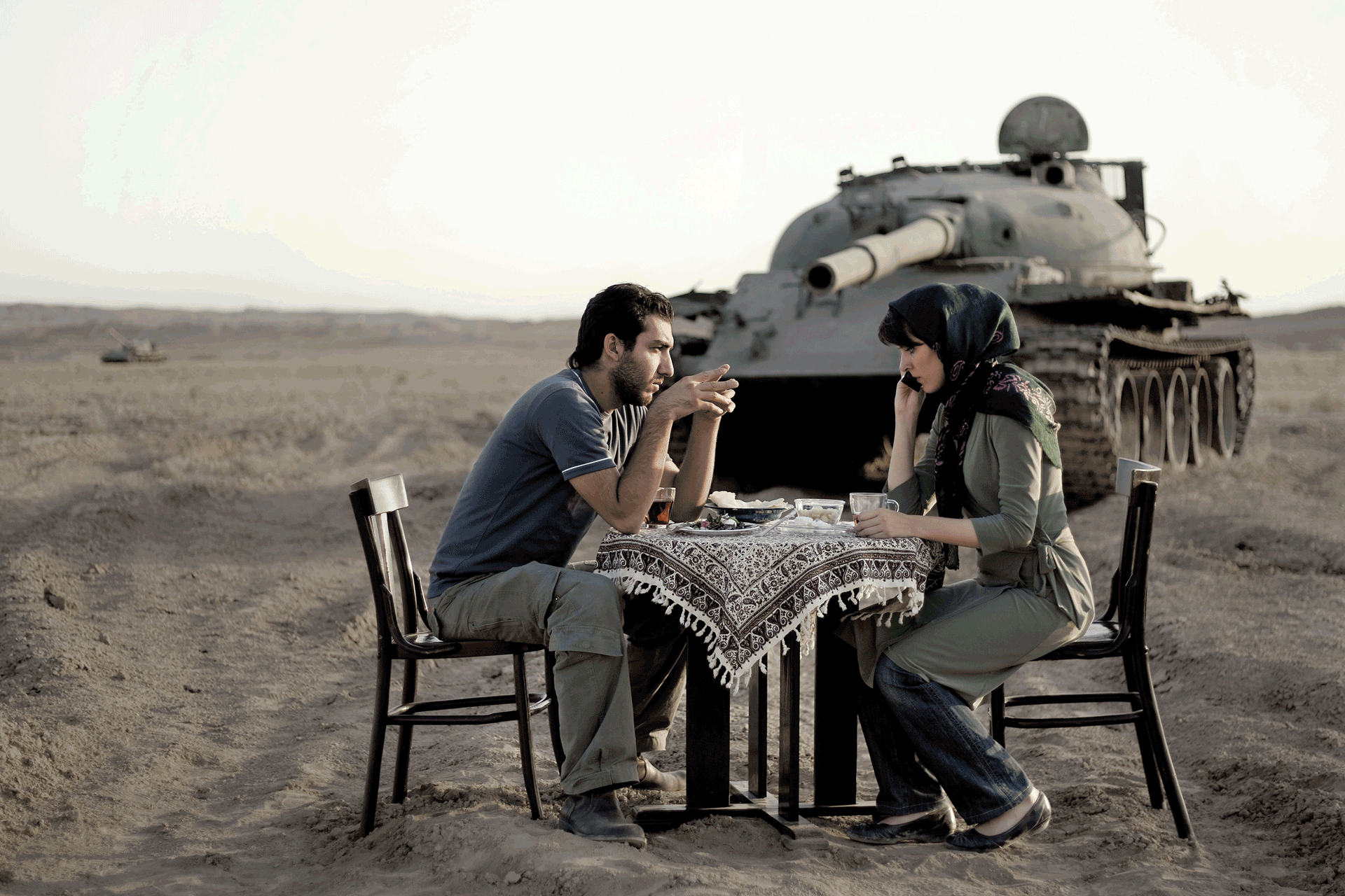 Man and woman sit at a table with a tank behind them.