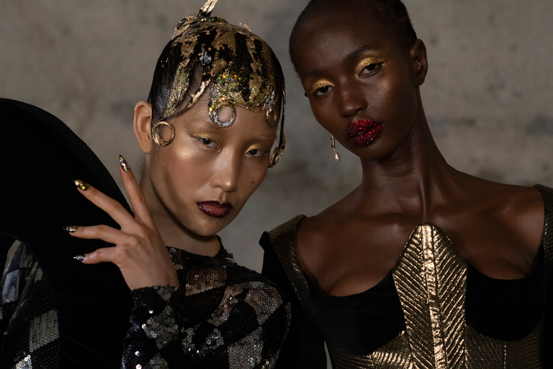 Close up of two models' faces with gold makeup