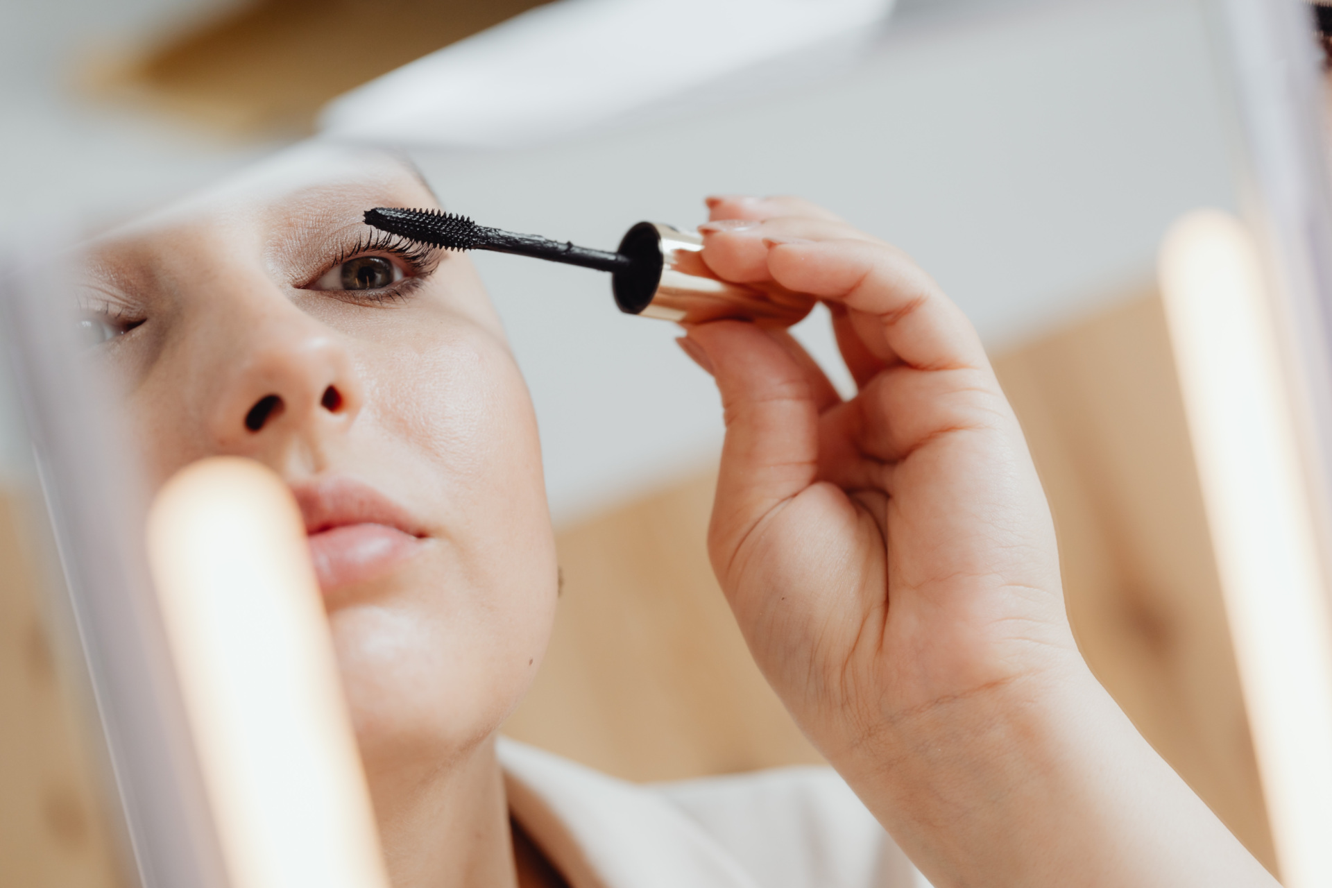 Woman applying mascara in a mirror