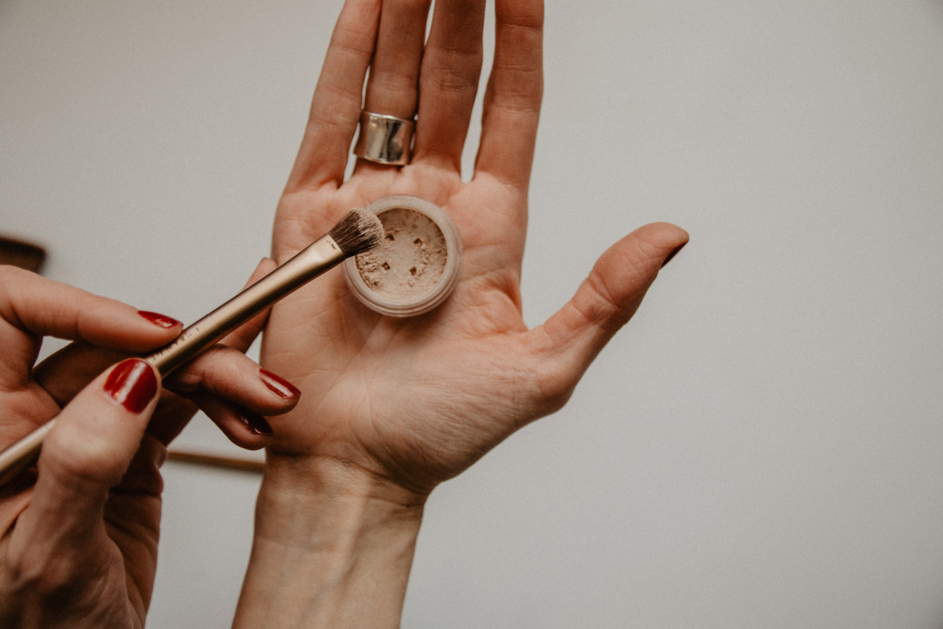 Close up of hand holding makeup brush and eye shadow pot