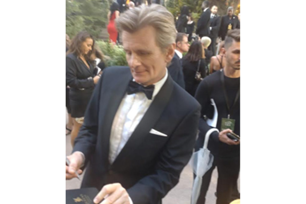 Charles Edward signing his autograph in a Queen’s College notebook at Amazon’s Lord of the Ring series premier at Leicester square
