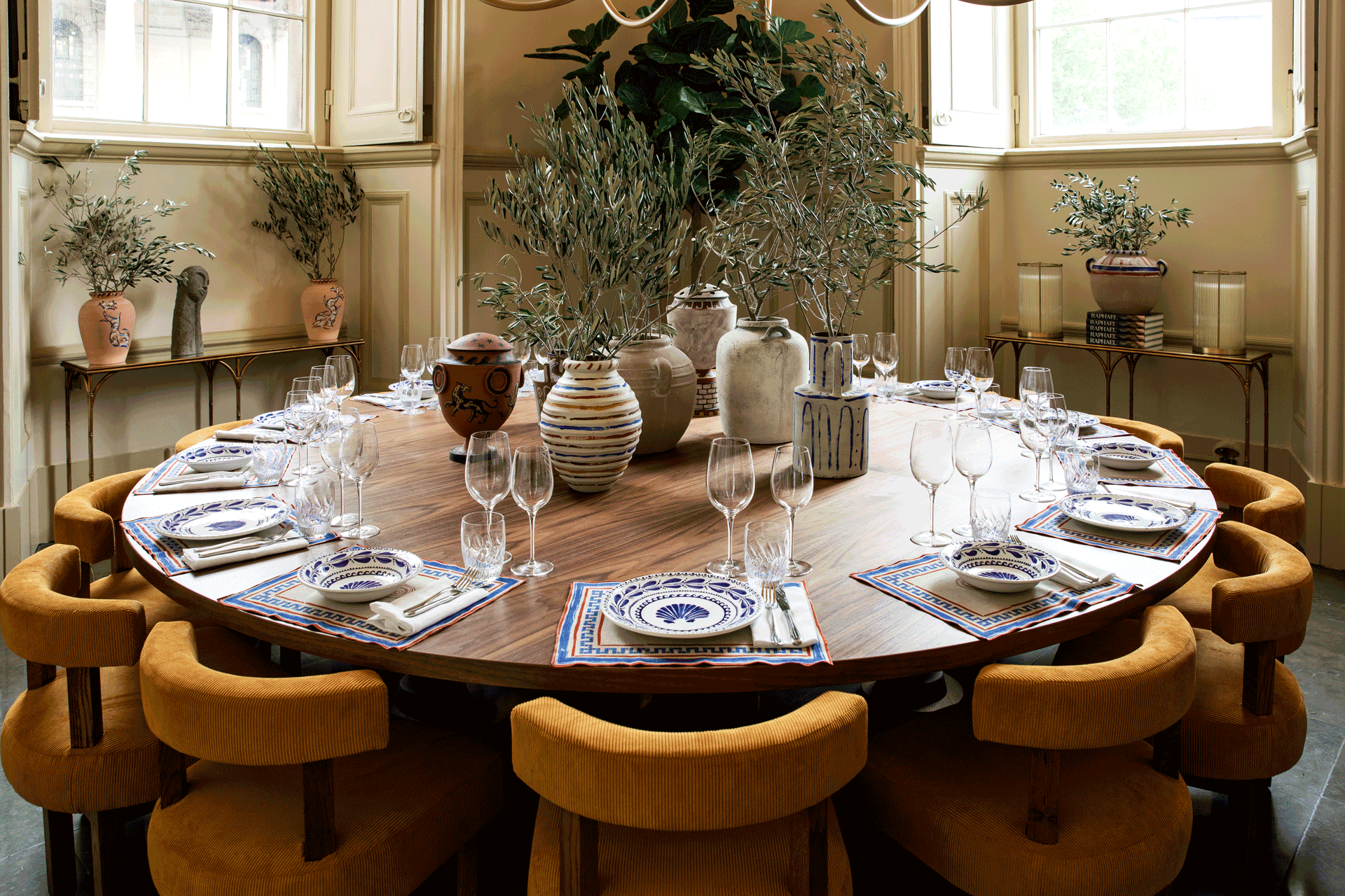 Circular wooden dining table with curved ochre-yellow chairs.