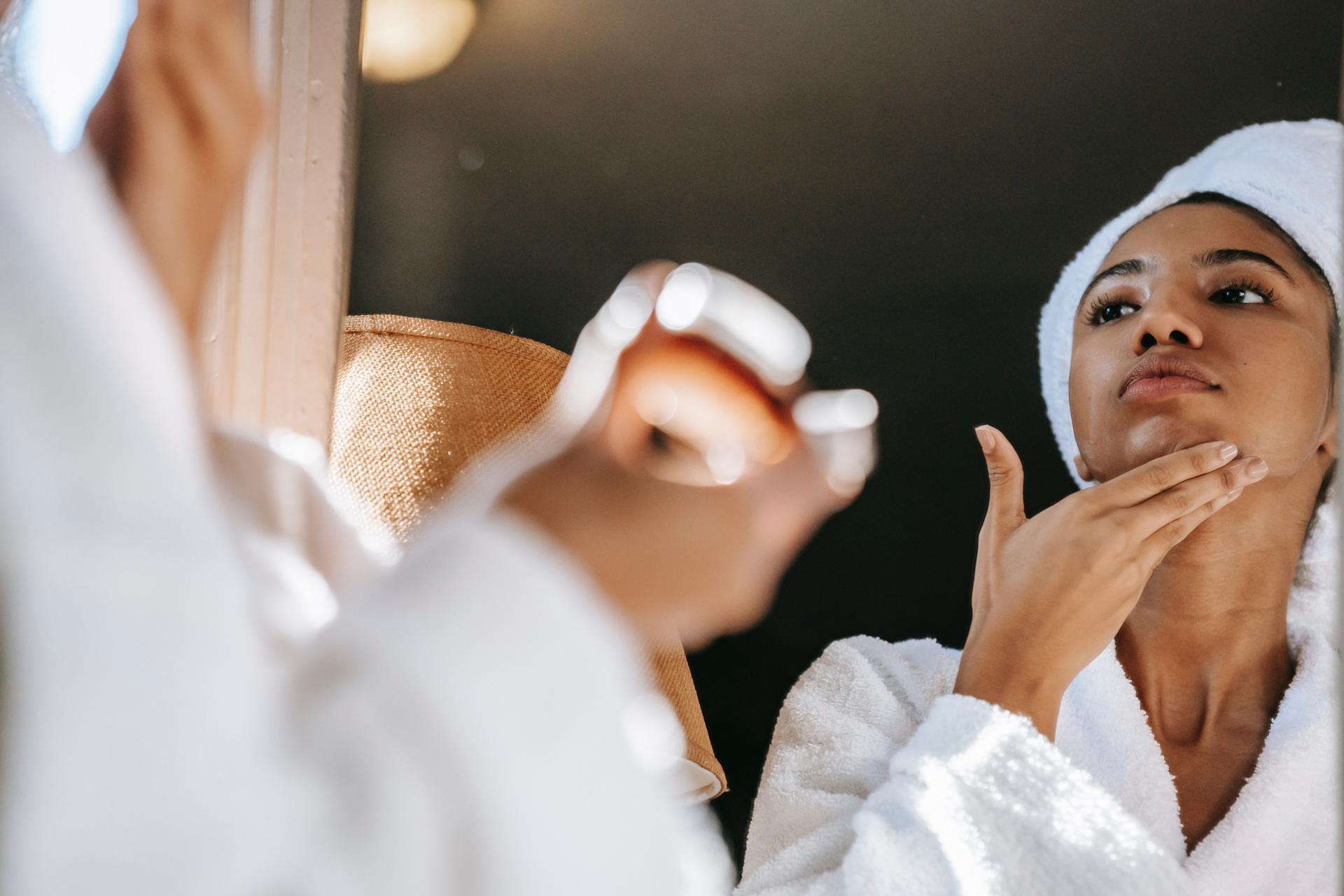 Woman putting cream on her skin in the mirror