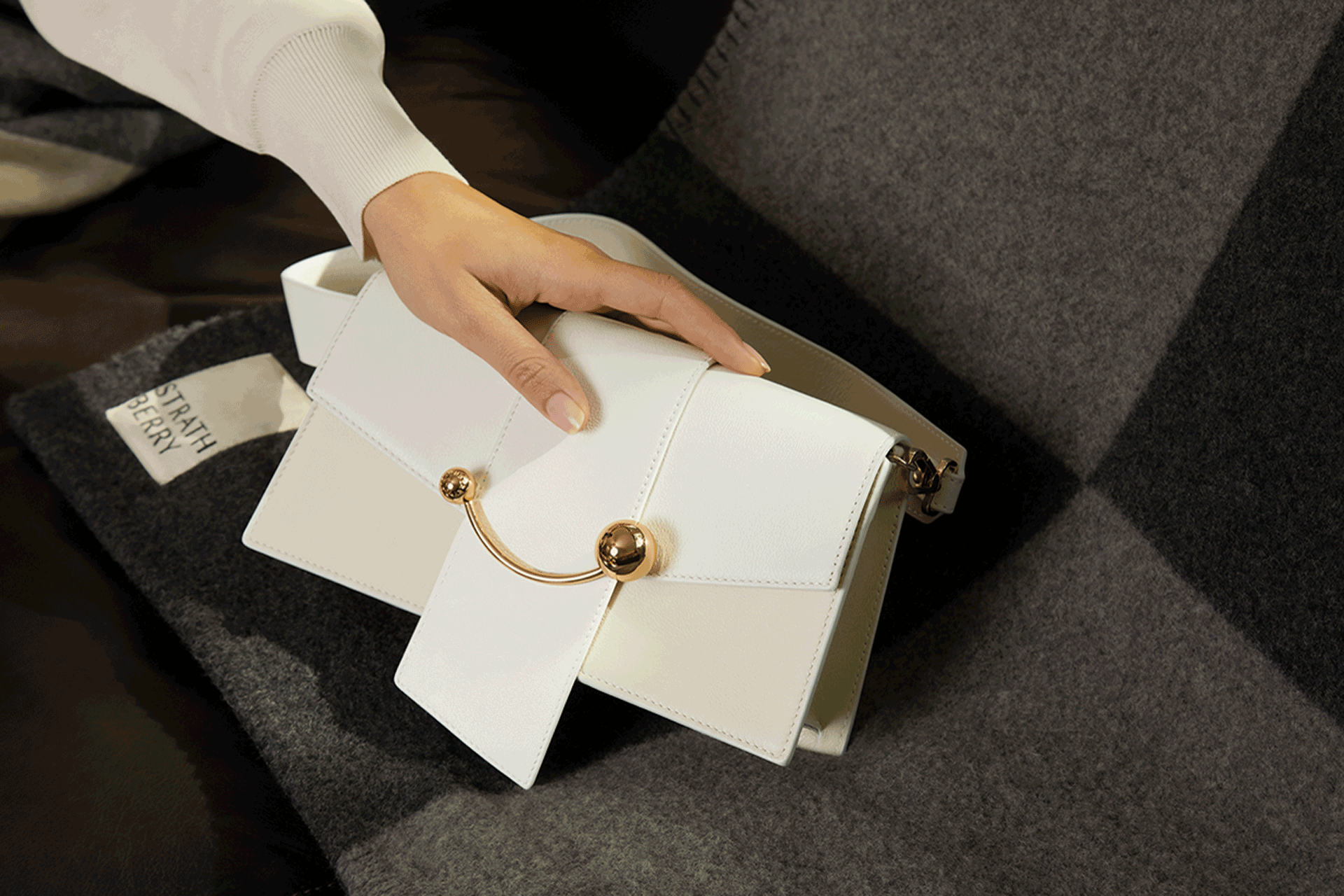White leather Strathberry bag with a gold clasp.