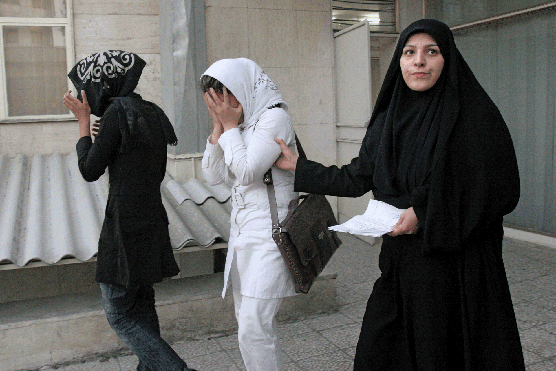 A female police officer leads two young women into a police station
