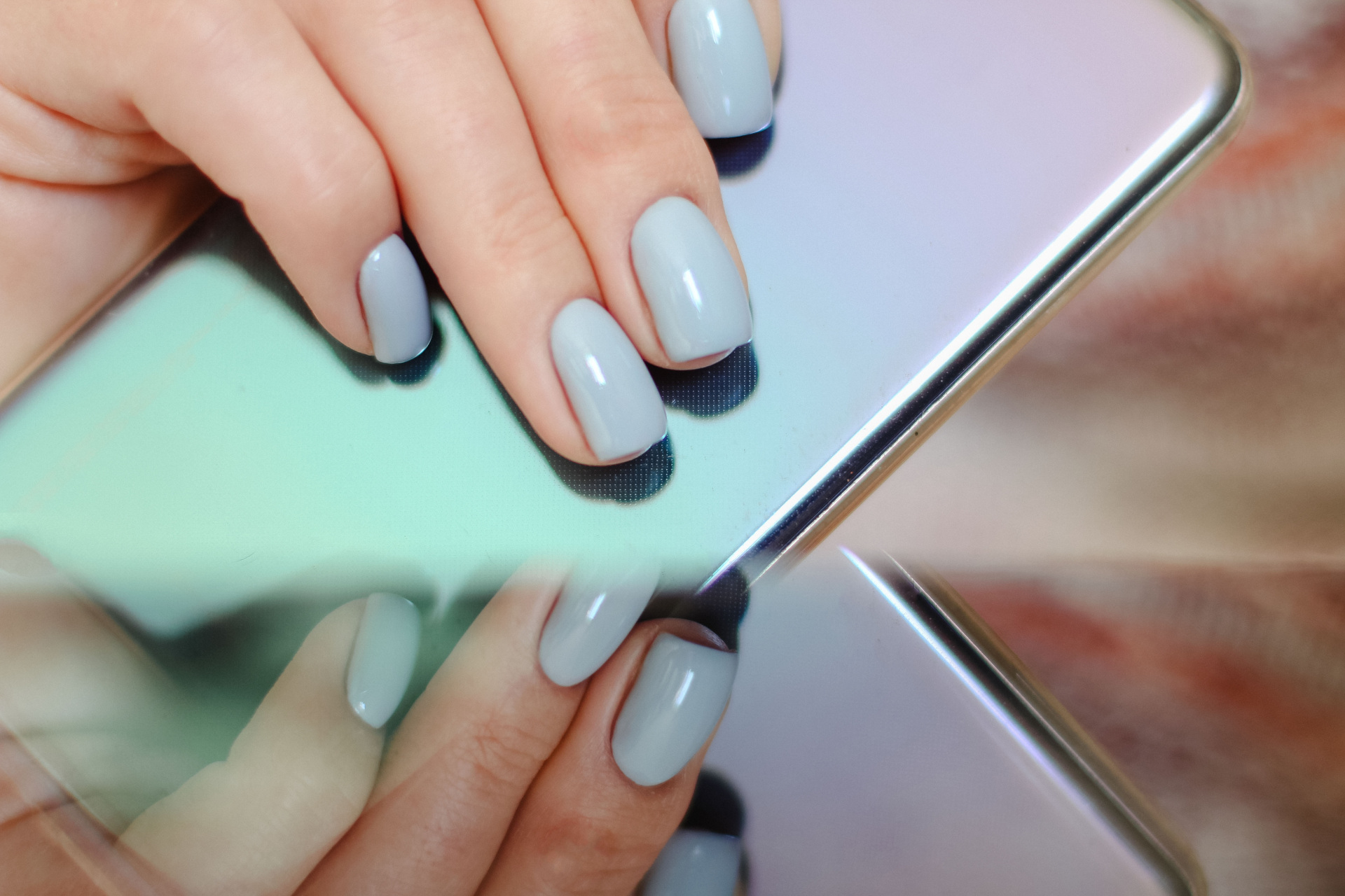 Hand with blue nails reflected in metallic surface