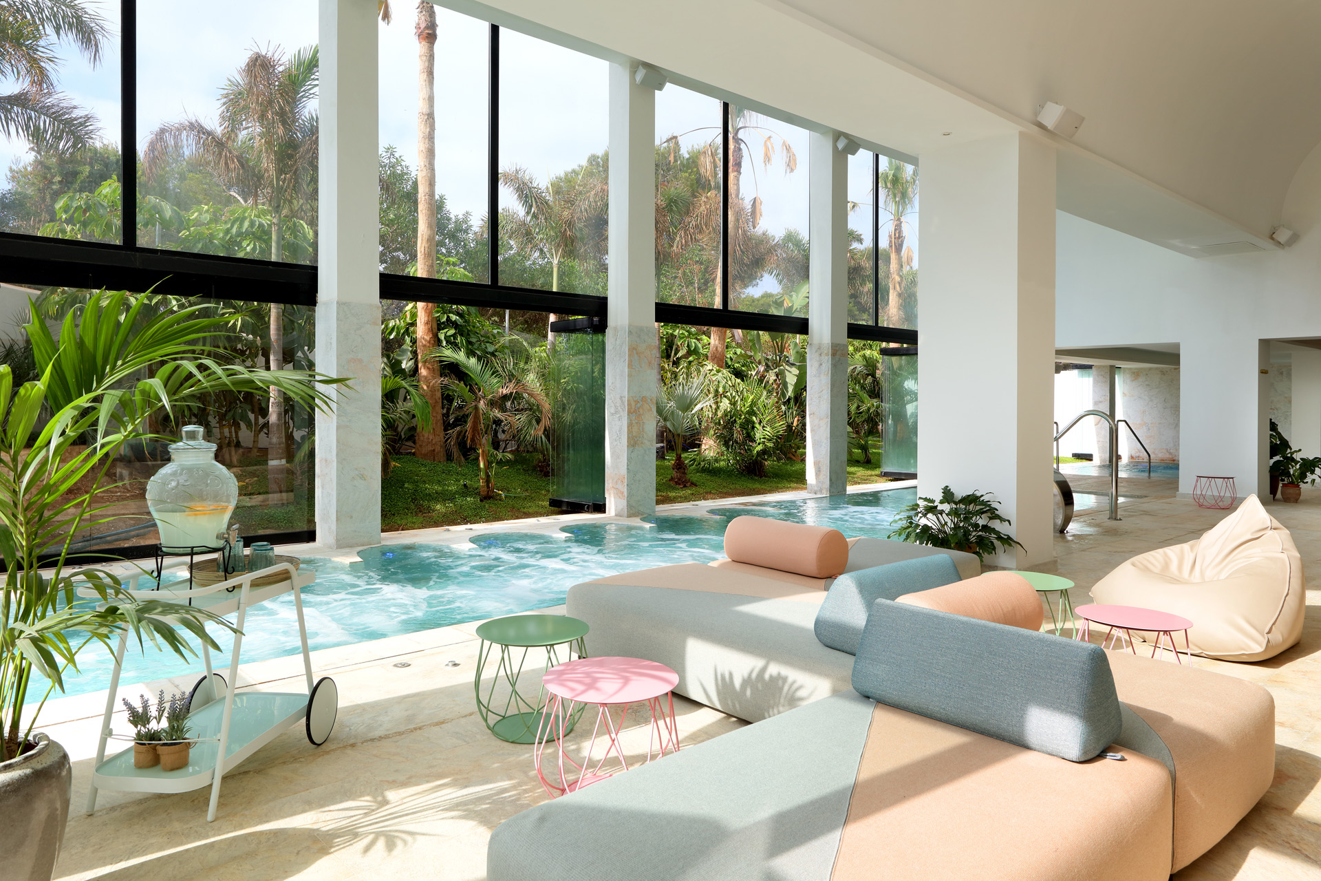 Spa at Bless Hotel Ibiza, featuring pastel pink and blue modular sofas and a hydrotherapy pool,.