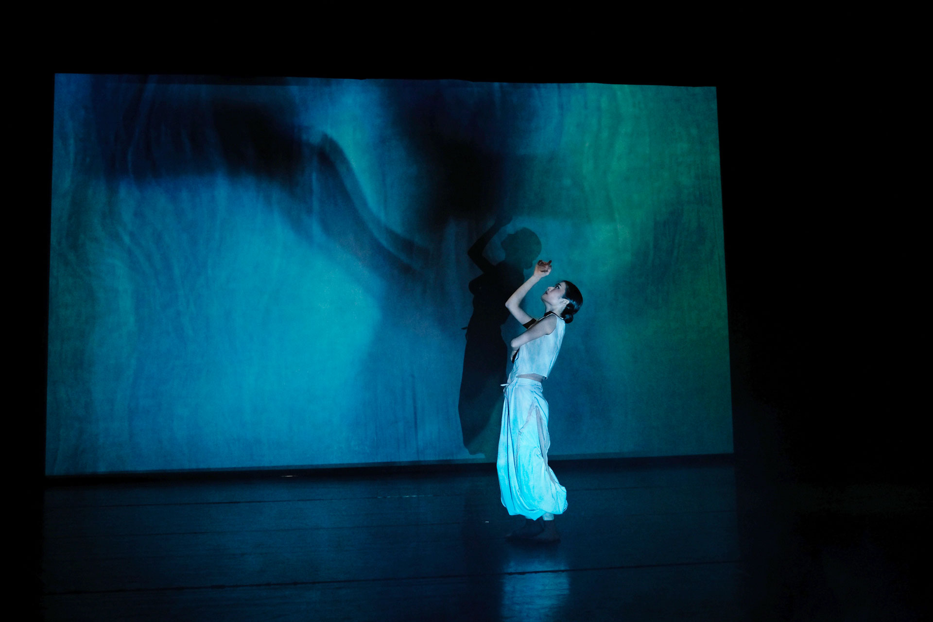 A dancer in front of a lit up colourful screen