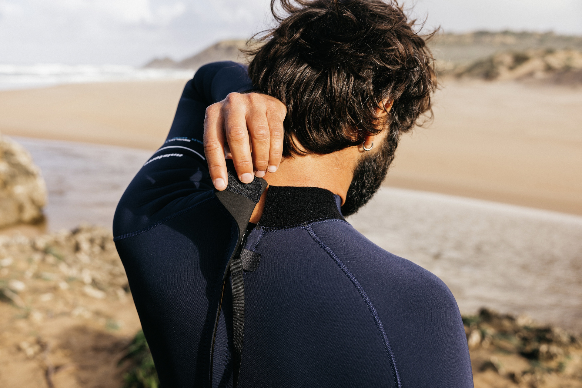 Close up of man zipping up his own wetsuit