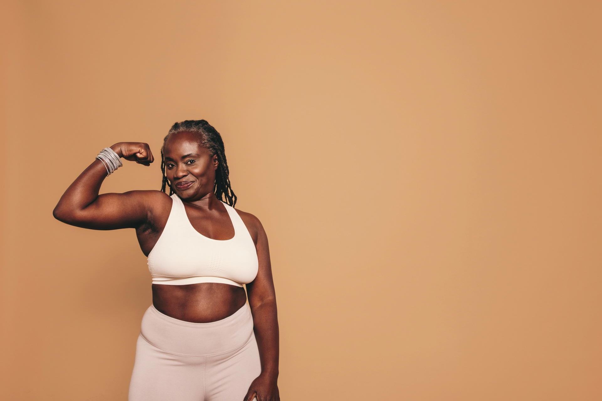 Mature woman flexing her bicep in a studio