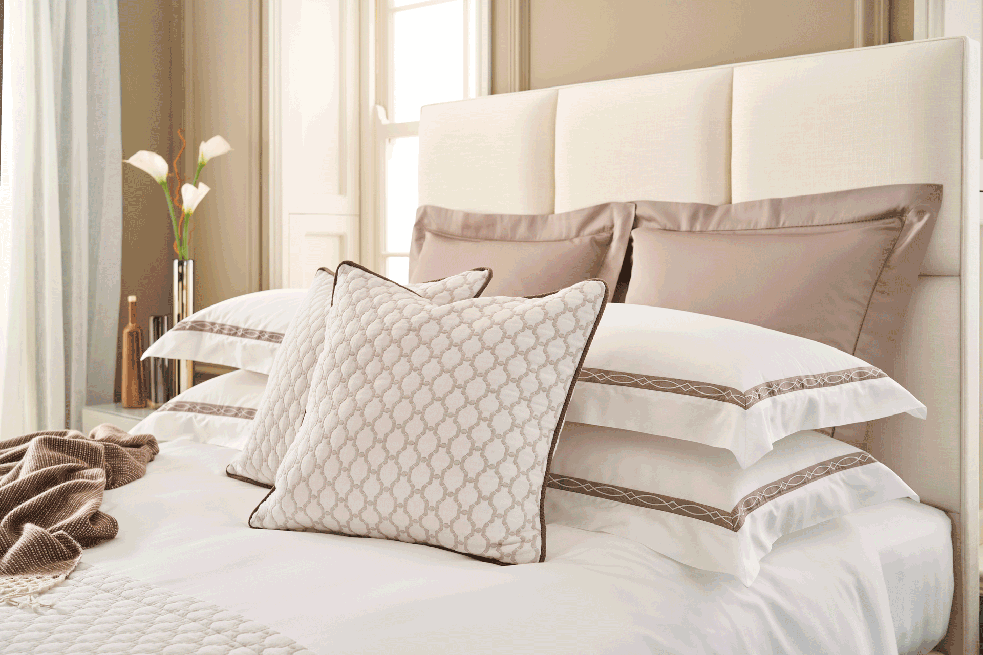 White bed linen with taupe trim and square taupe cushions