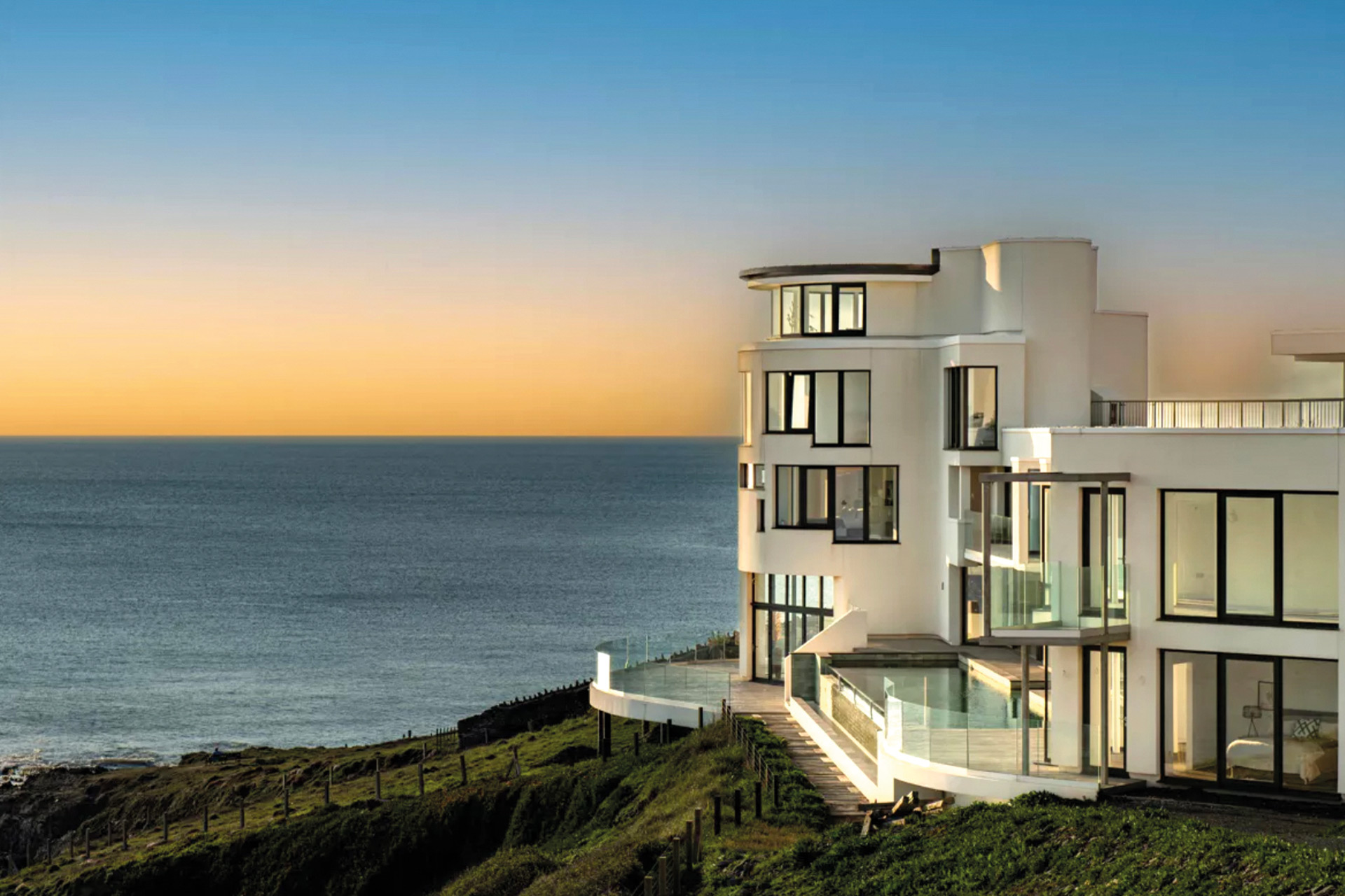 Waterfront eco property with large grey-framed windows and rounded walls