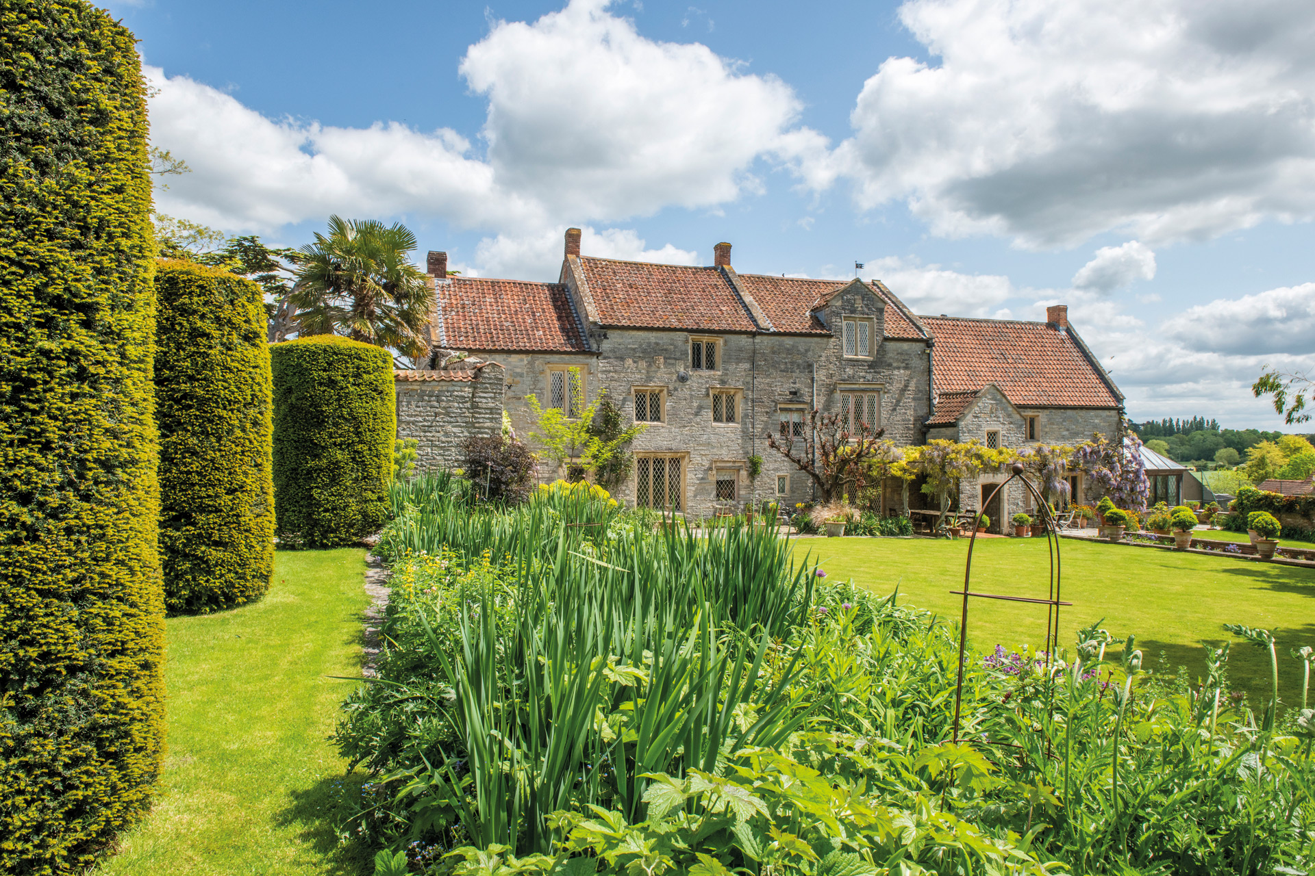 Large farmhouse with lawns and landscaped hedges