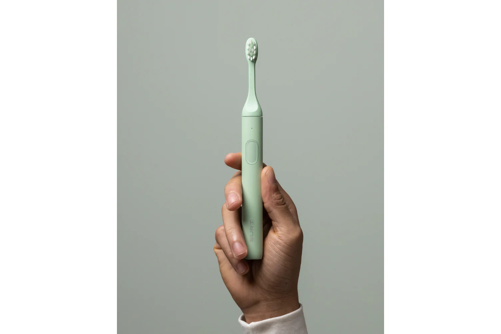 Hand holding green toothbrush