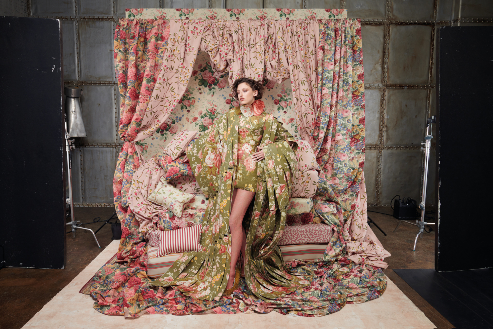 Woman in floral robe surrounded by pink curtains and fabric