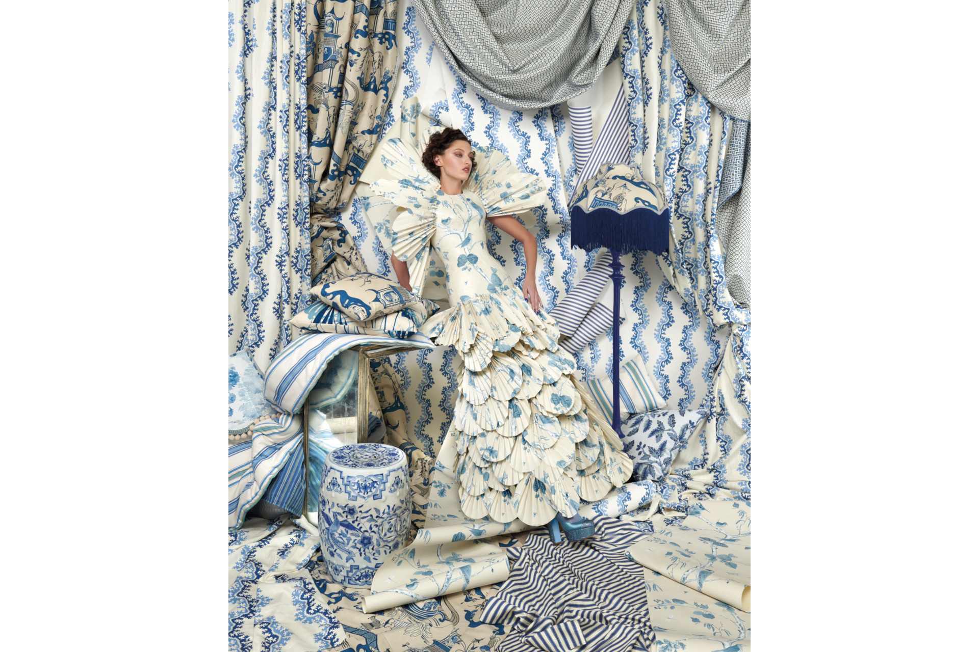 Woman in white and blue dress surrounded by blue curtains and fabric 