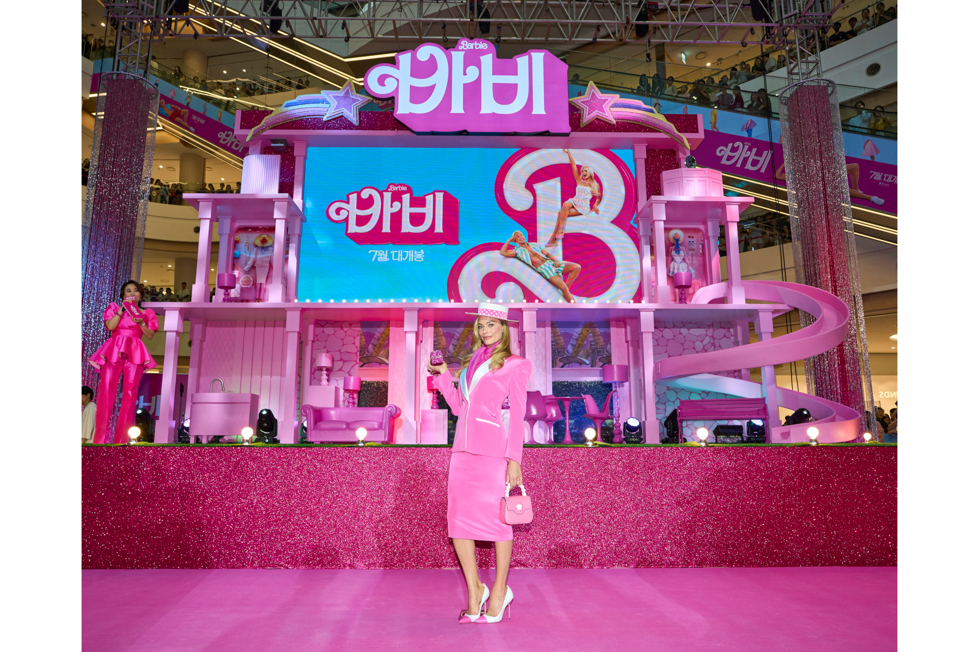 Margot Robbie in pink outfit in front of Korean film poster