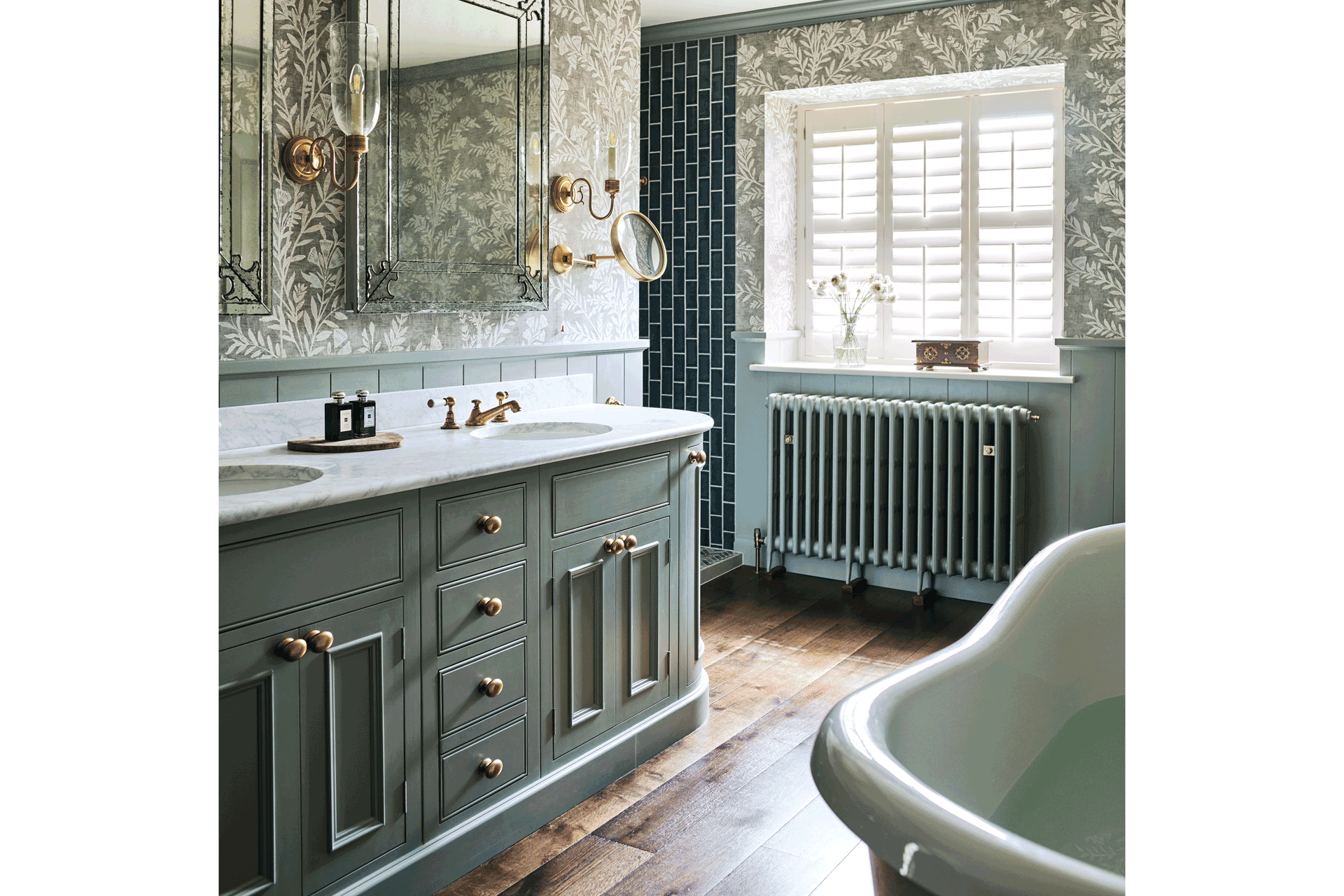 Bathroom with roll-top bath and blue cabinets with marble worktops