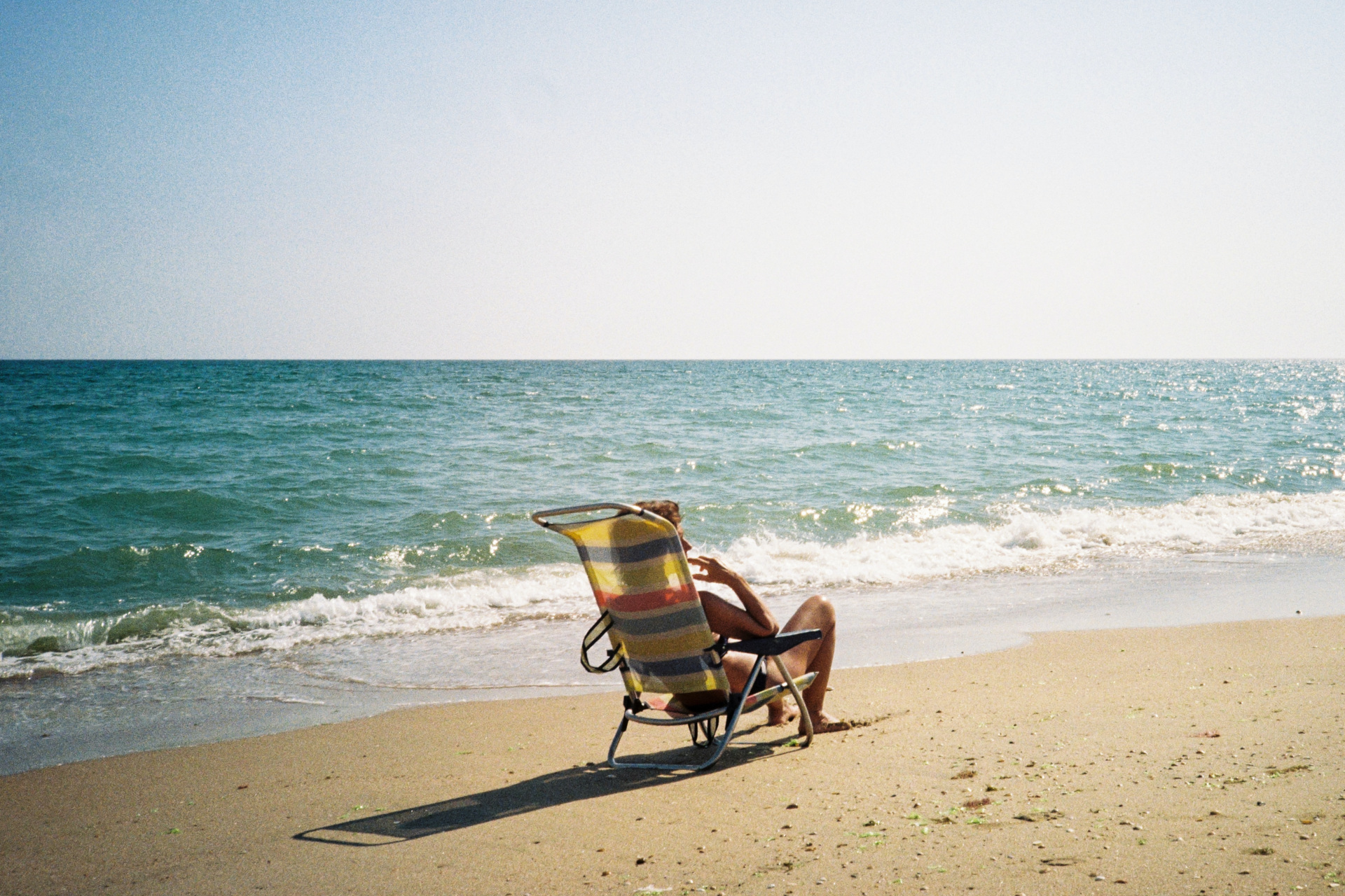 Person sunbathing in chair on beach