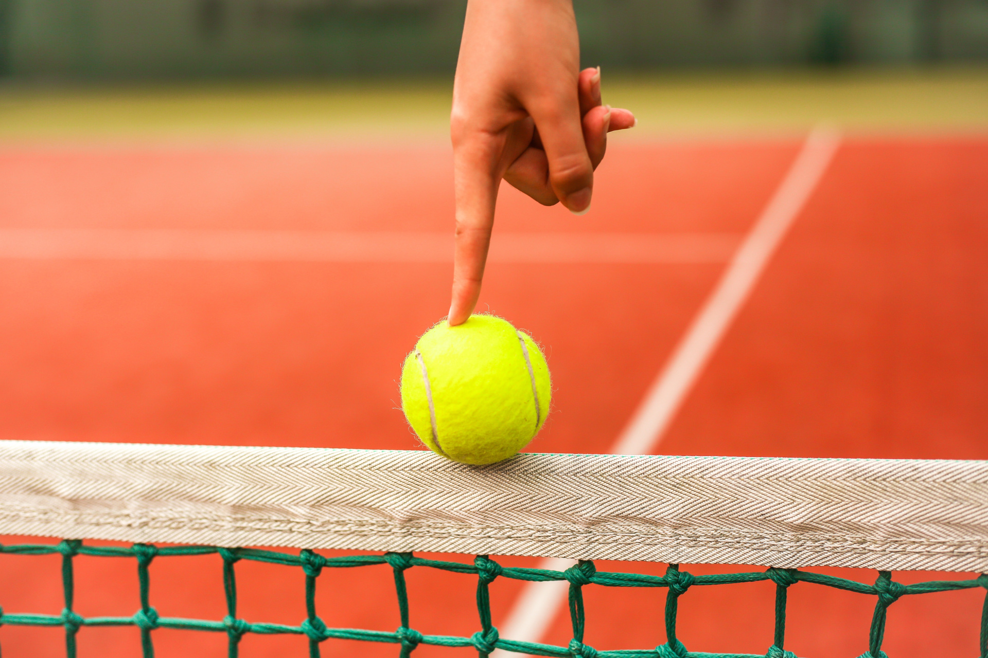 Hand balancing tennis ball on net