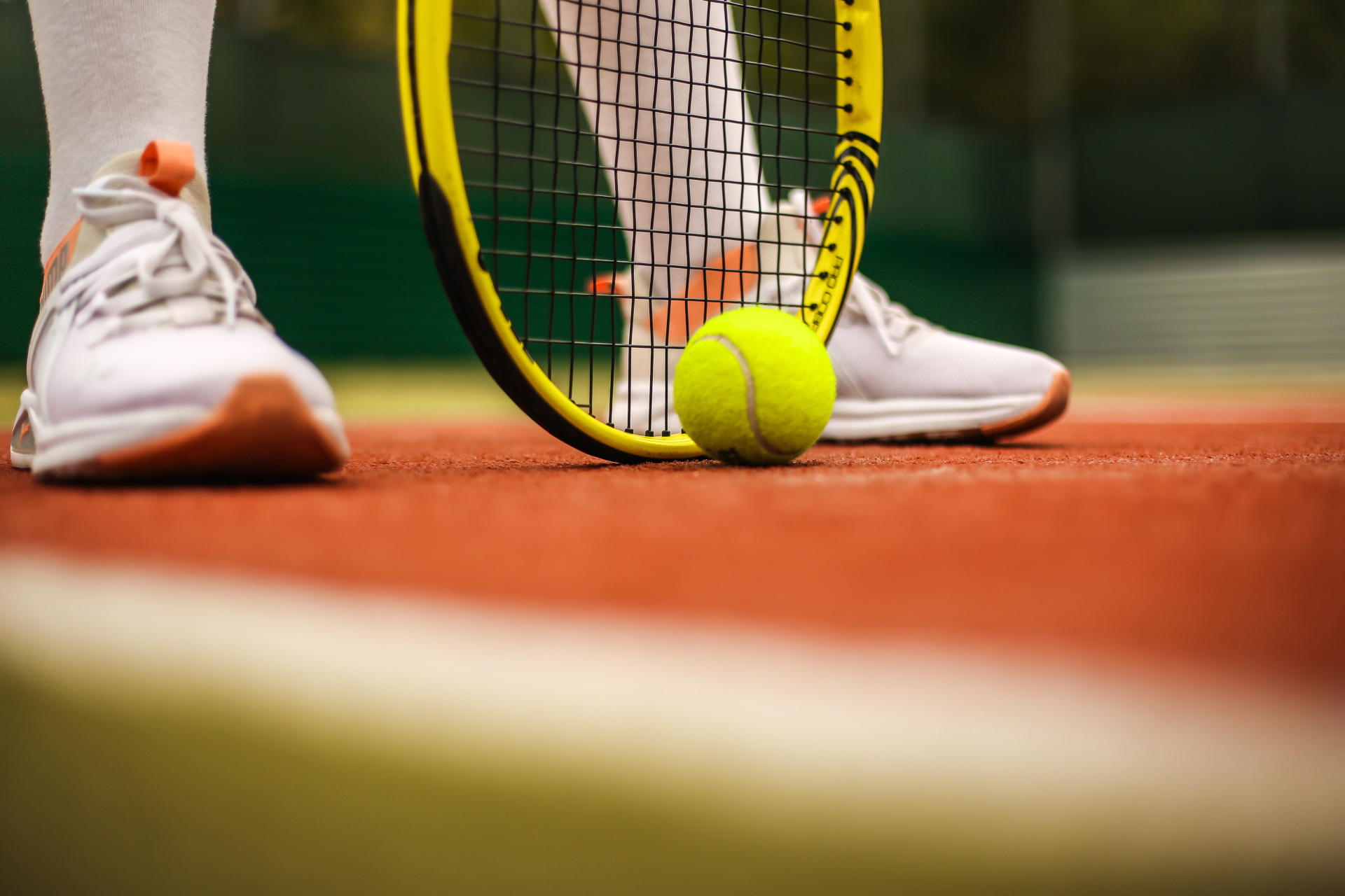 Close up of feet with tennis racket and ball on court