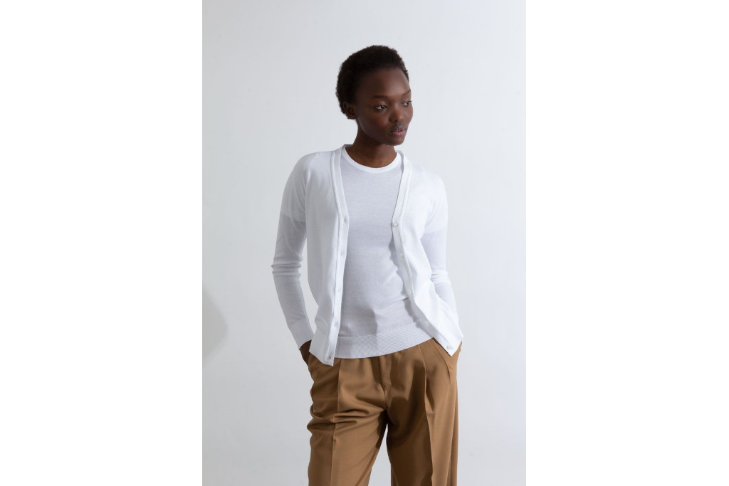 Woman in white top and cardigan, with brown trousers