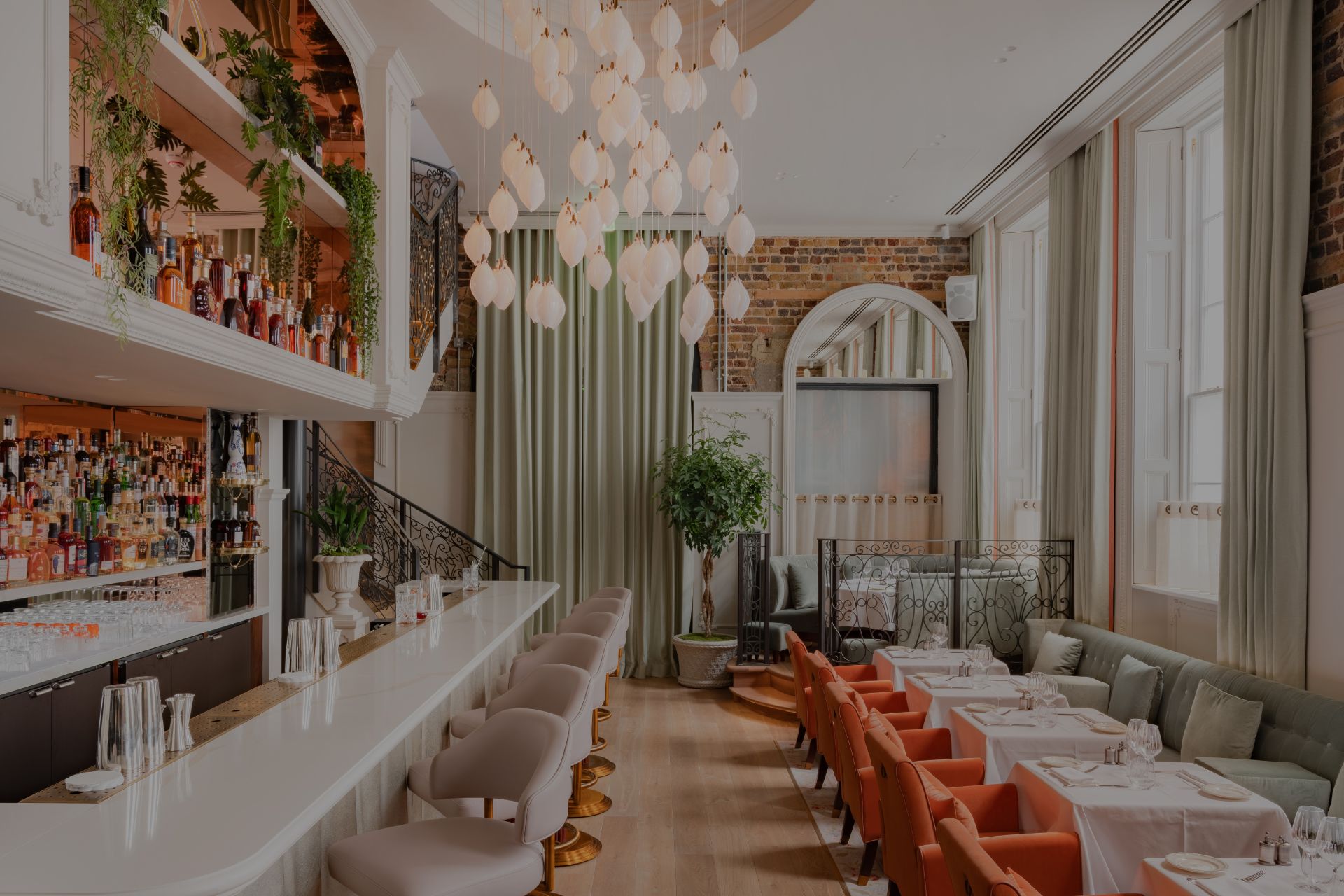 Restaurant with pendant chandelier. white tables and red seating