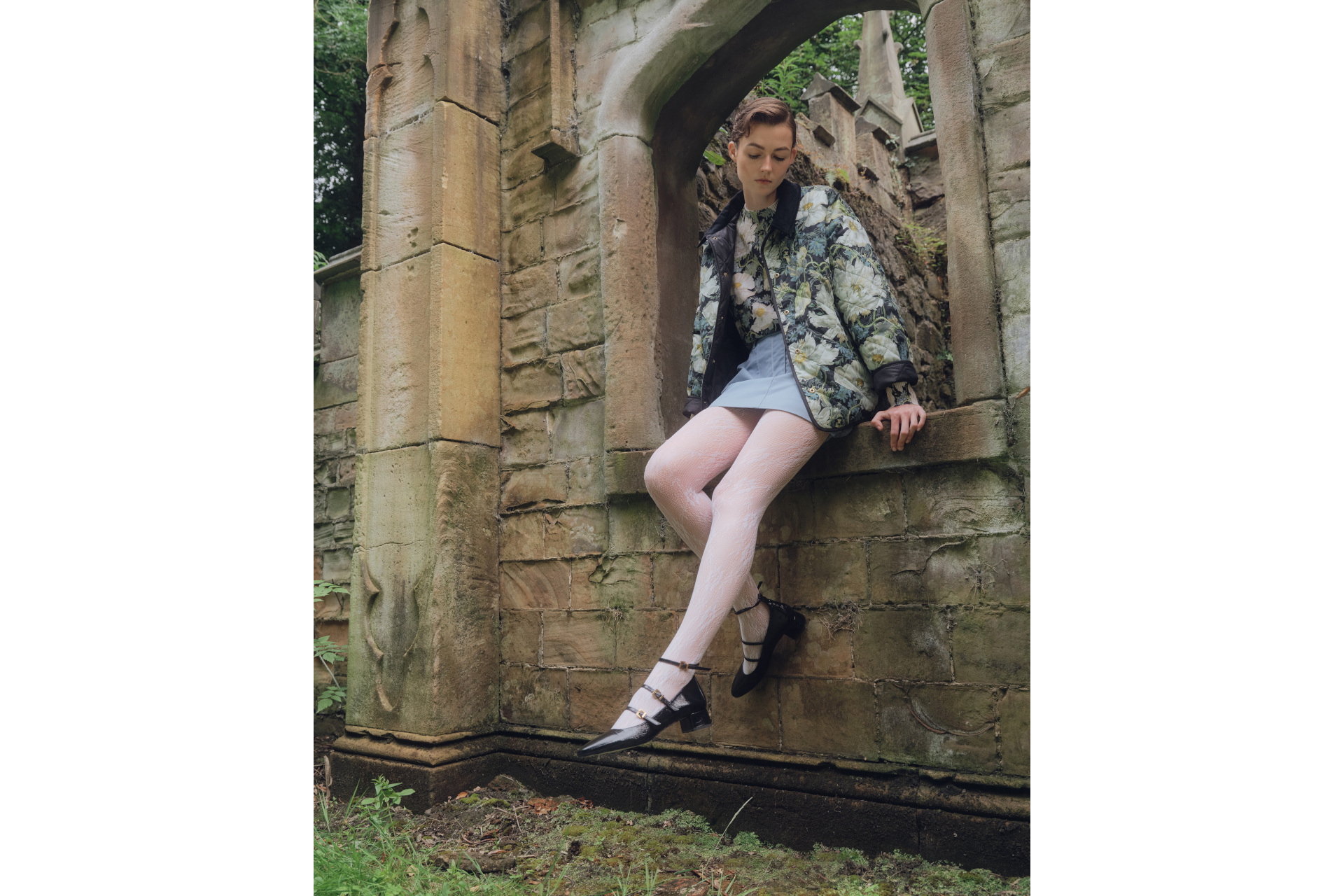 Woman sat in ruined building surrounded by nature