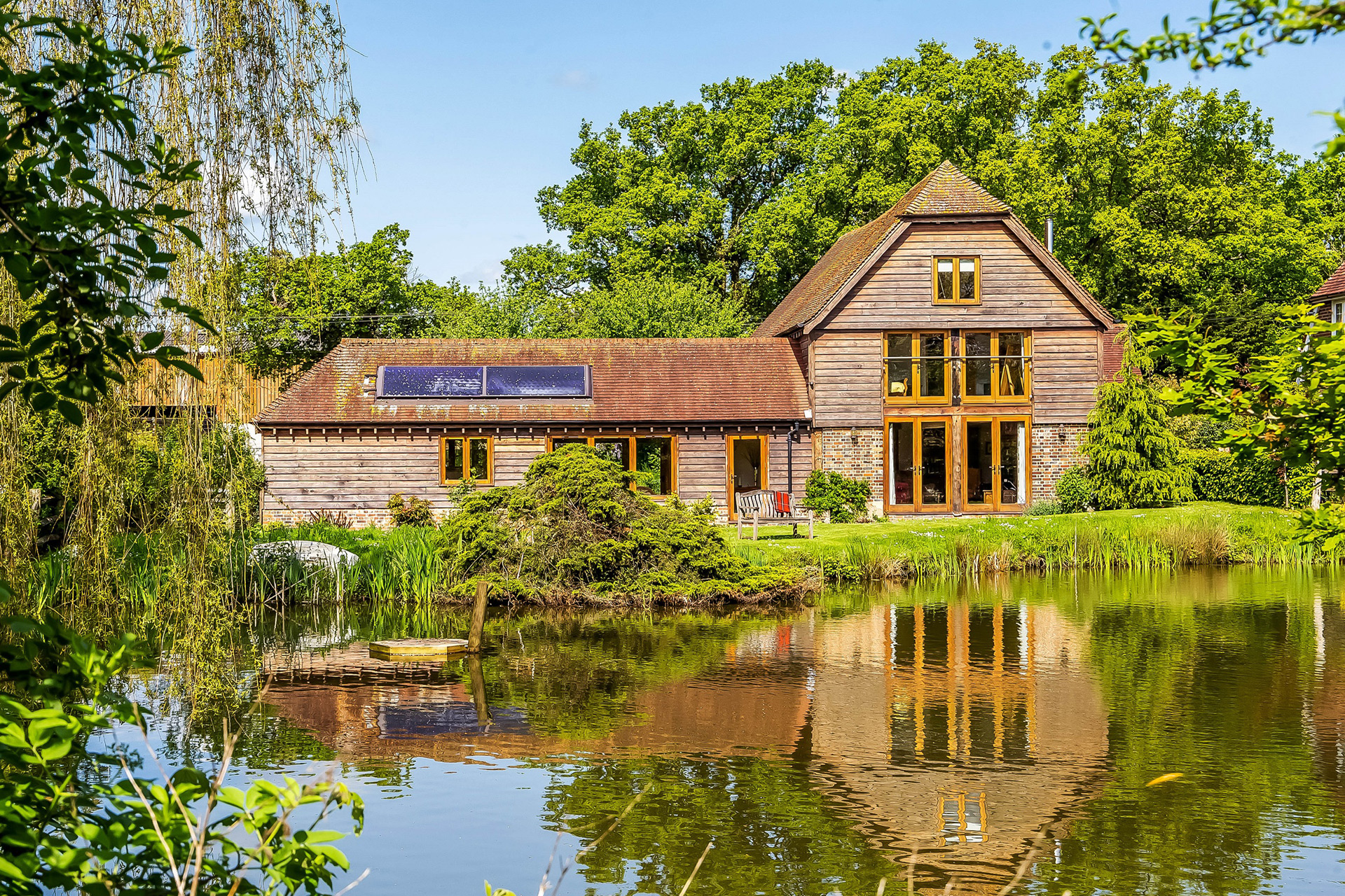 Exterior of wooden-clad barn with a pond in front