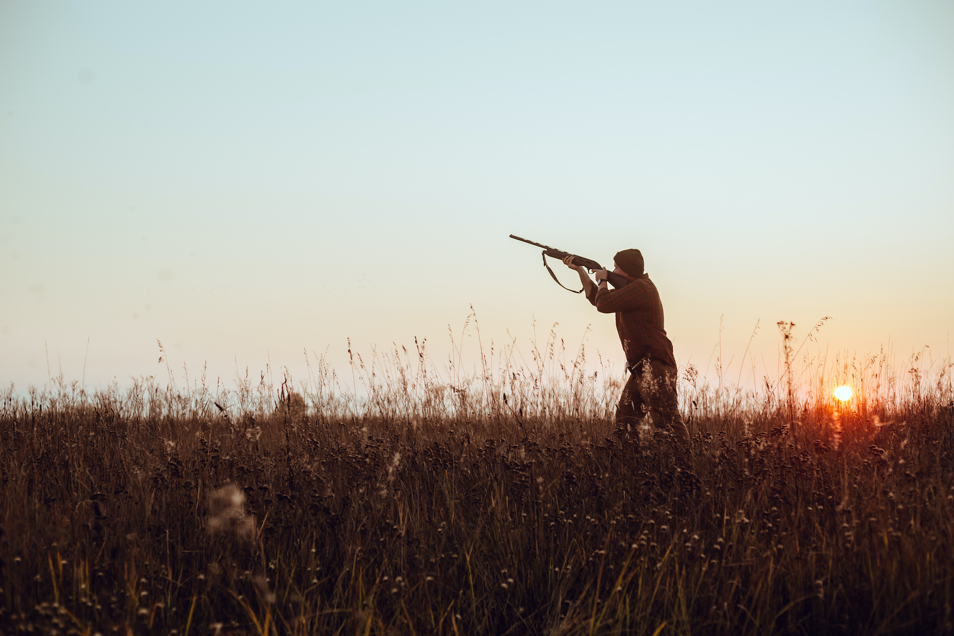 Country sports Hunter's dark silhouette with blue sky and red sun - photo with selective focus
