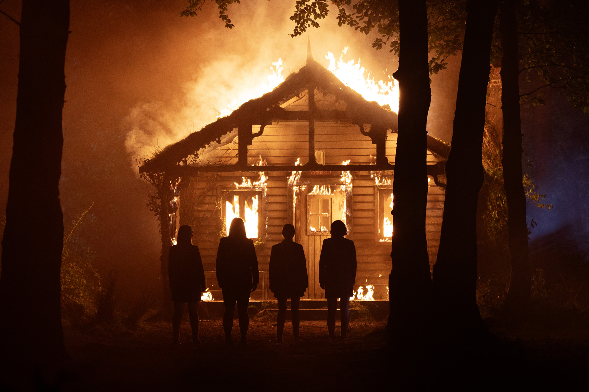 Four people silhouetted against a burning house