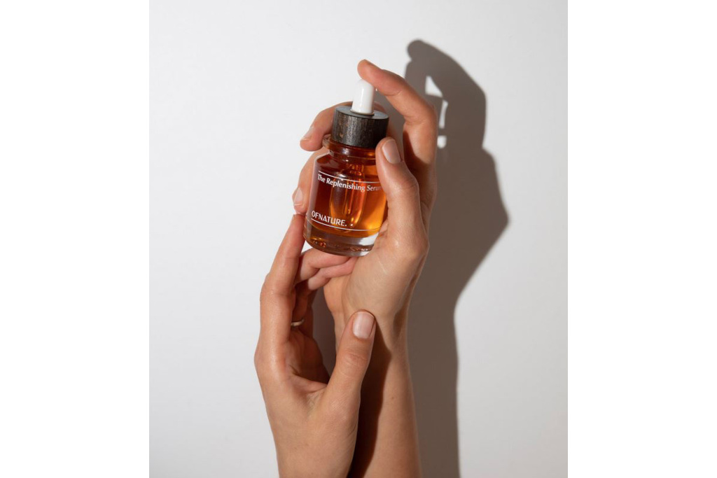 Hands holding up orange serum bottle | organic beauty brands