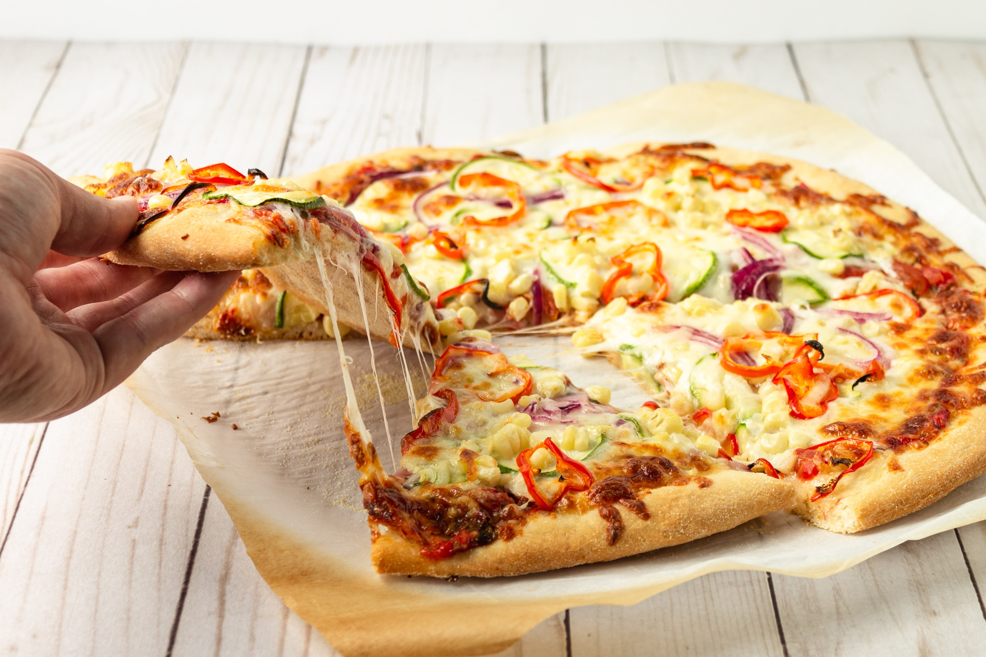 Someone pulling slice of pizza from pie