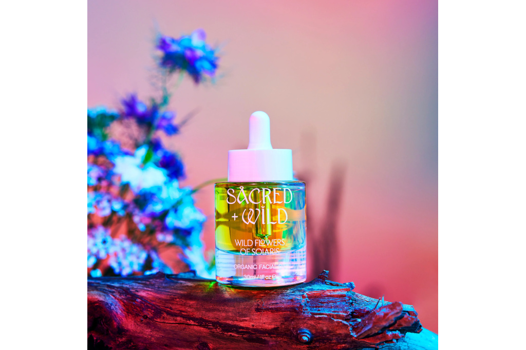 Serum bottle on pink-ish background, with log and flowers