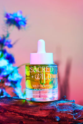 Serum bottle on pink-ish background, with log and flowers | organic beauty brands