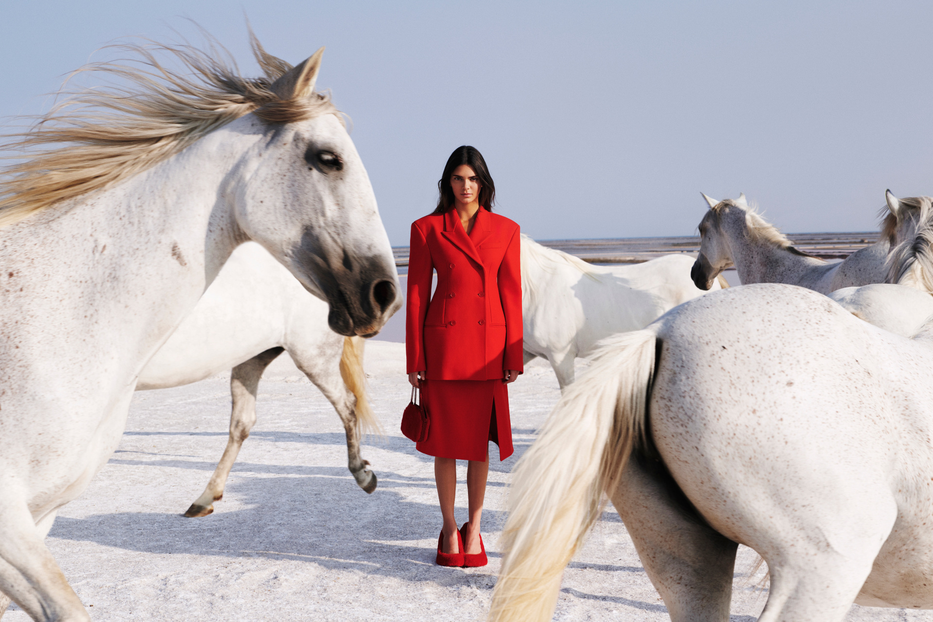 Kendall Jenner in red suit surrounded by horses