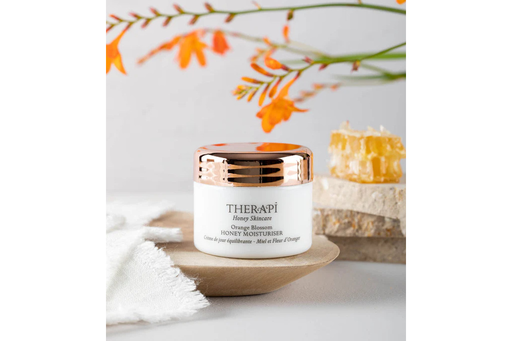 Skincare tub next to honeycomb and flowers