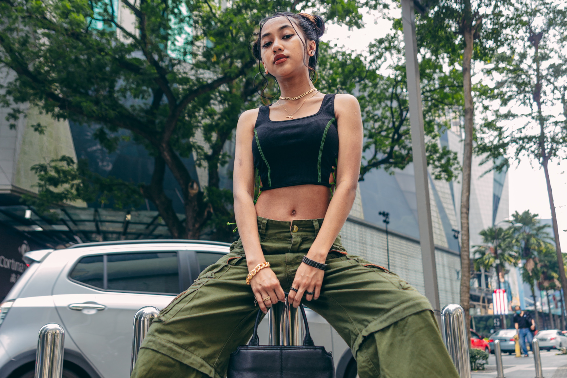 Woman sat on pillar wearing black top and green trousers