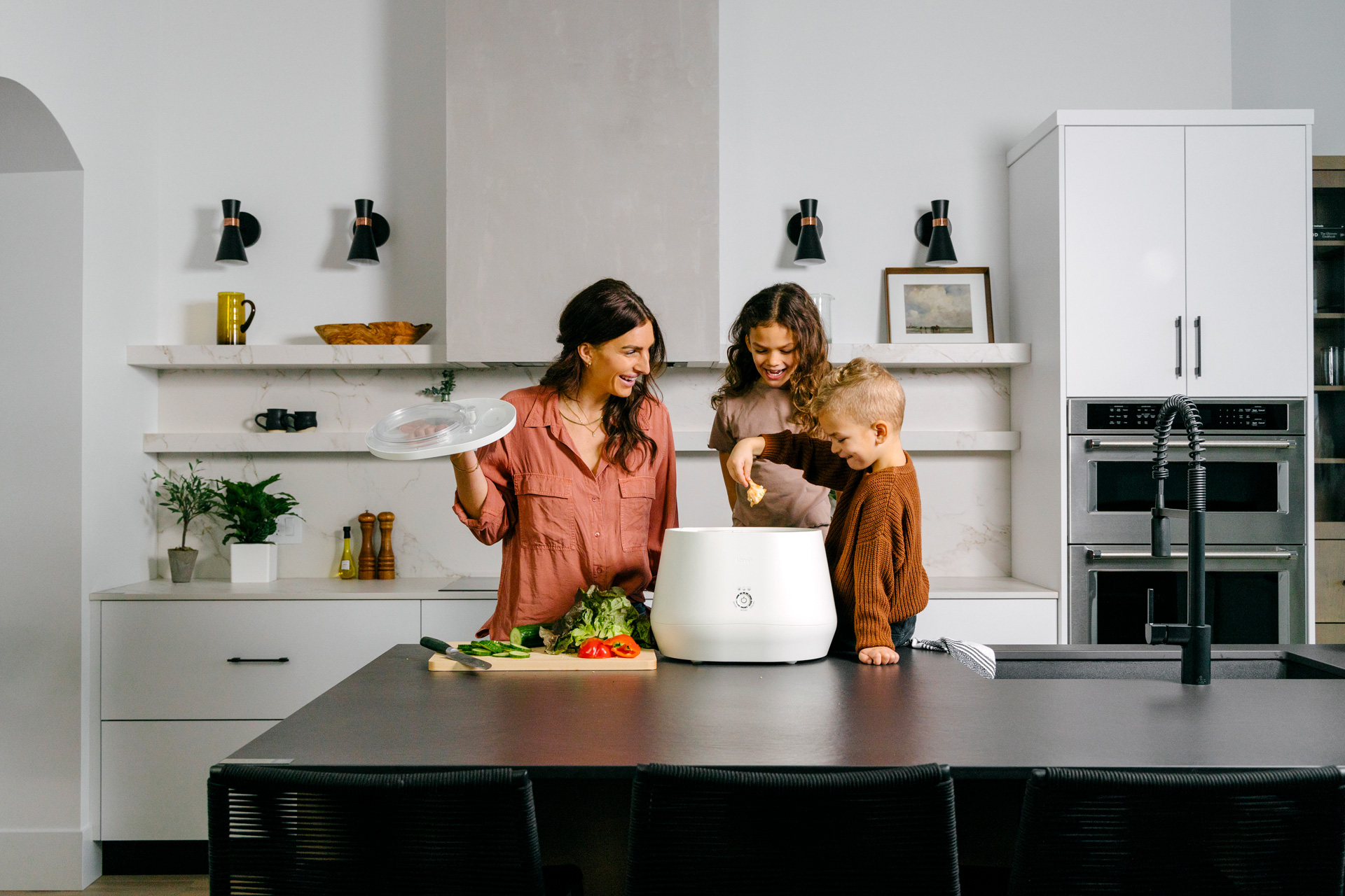 A mum and her children putting food waste into a composter