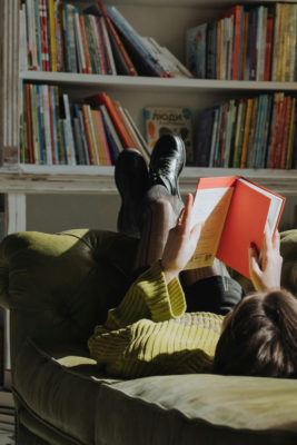 A woman reading a book on a sofa