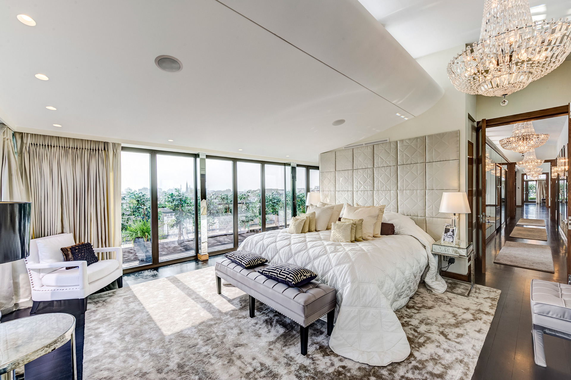 Penthouse bedroom with king size bed, gold accents and a chandelier.