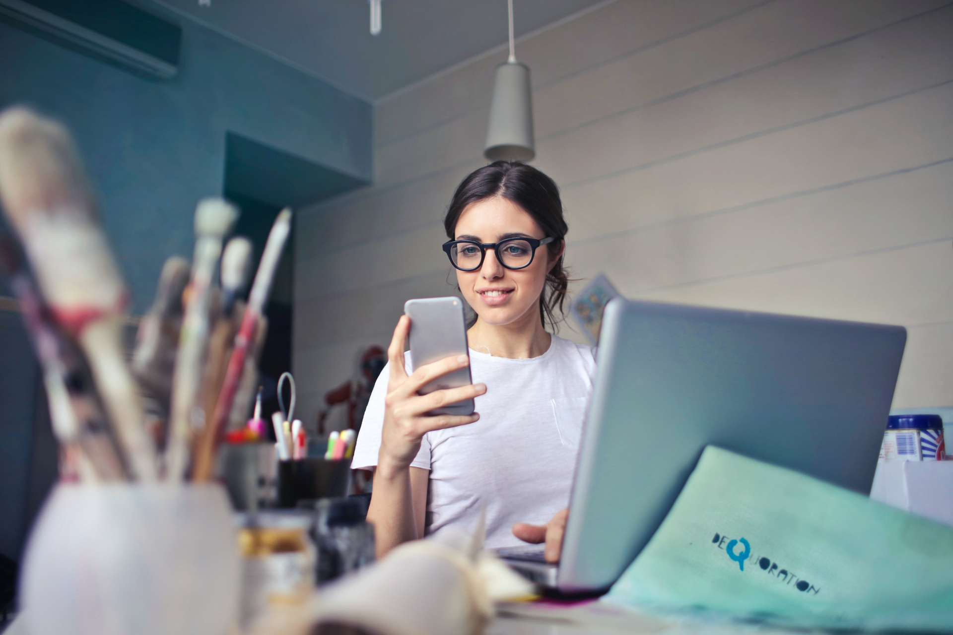 Woman on laptop looking at phone